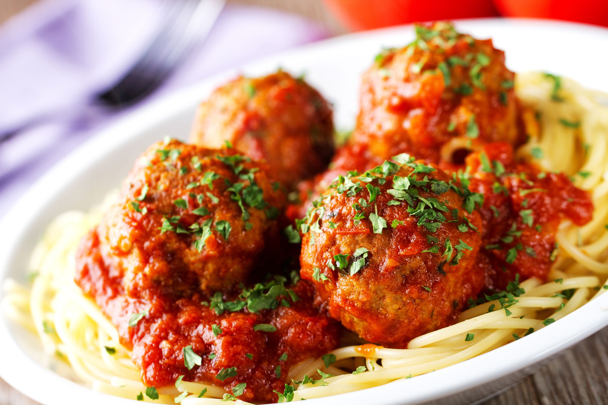 Spaghetti and meatballs on a white plate, selective focus, a slight diagonal with a blurred background of a fork and napkin