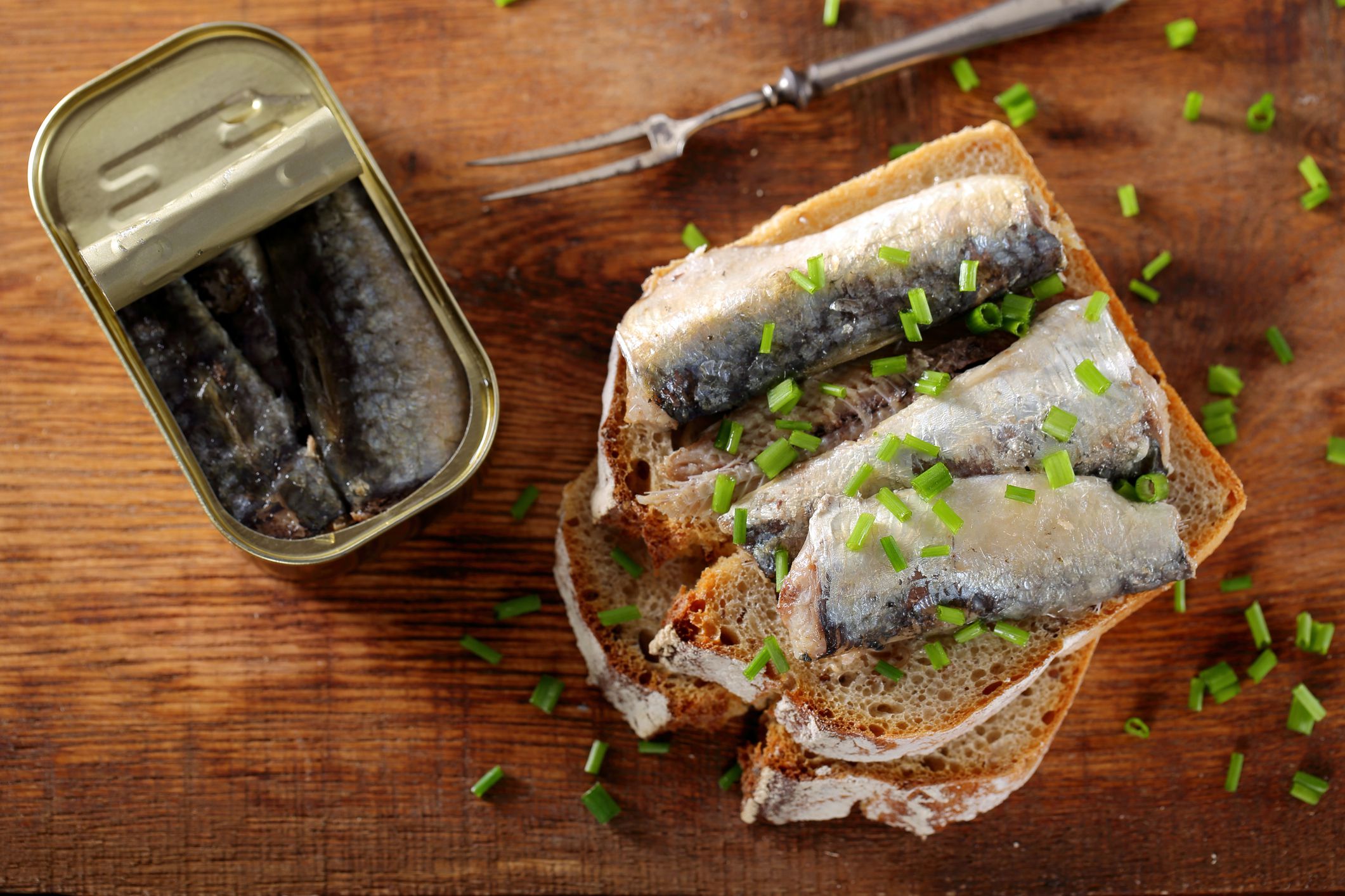 Toast with sardines from sardines in canned oil on a wooden table