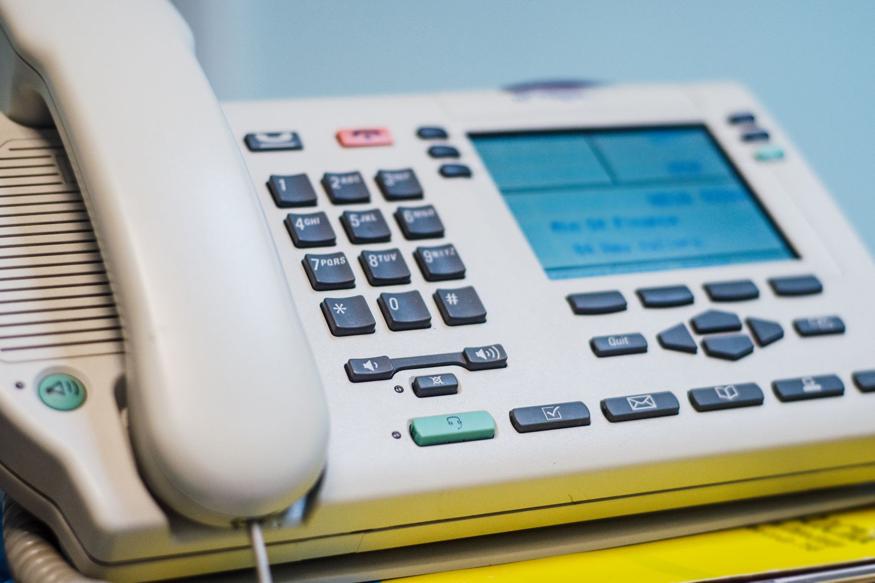 Traditional phone with handset on the left and caller ID on the right, selective focus, with a blurred background of grey-blue