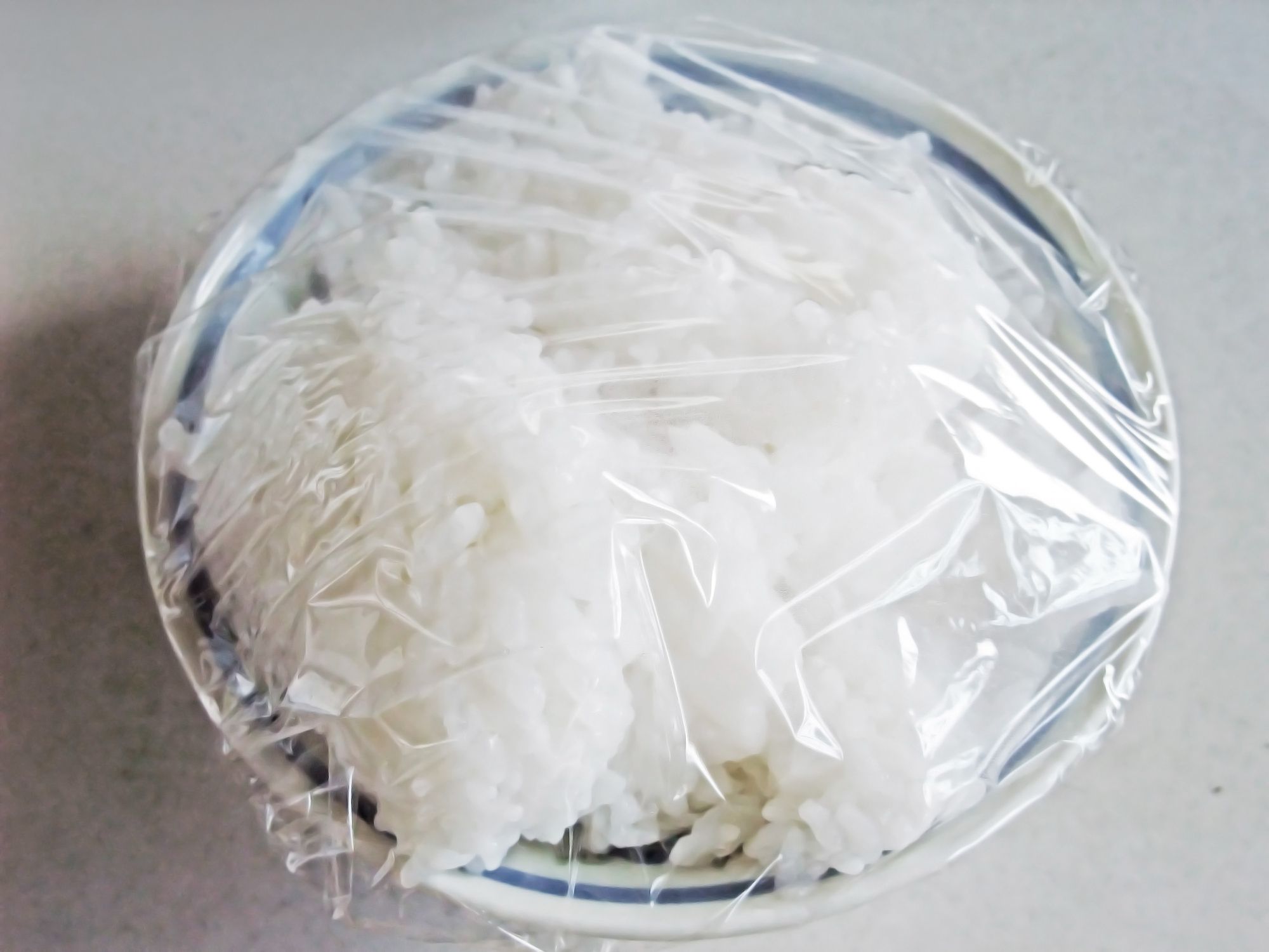 Leftover rice in a bowl covered with plastic wrap
