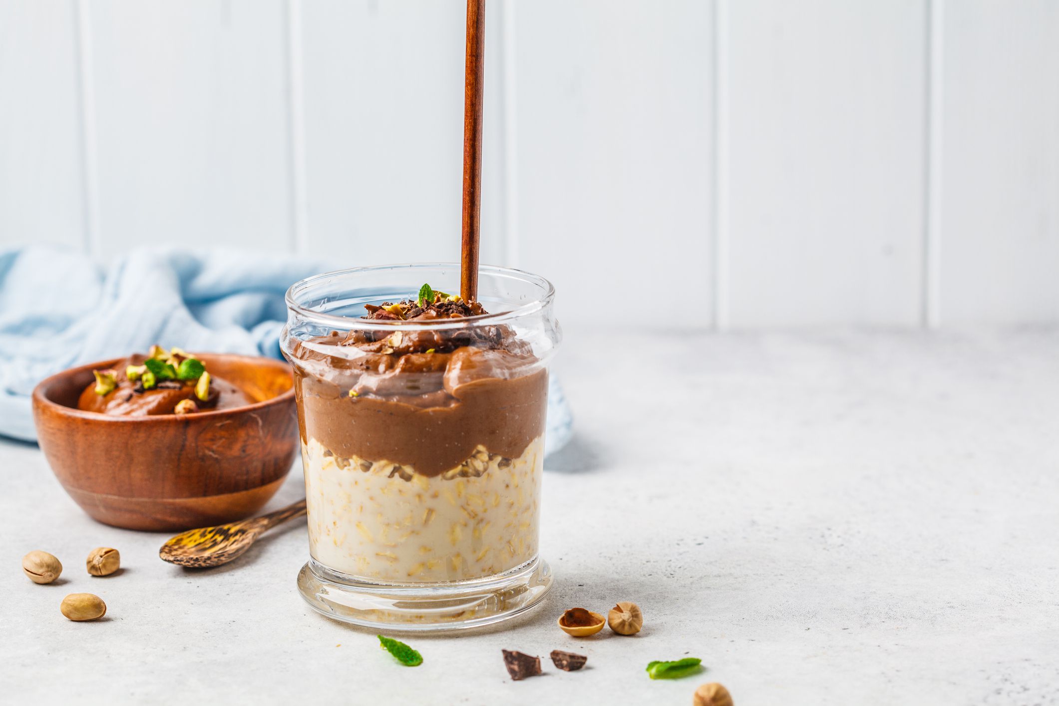 Overnight oatmeal with milk and chocolate mousse in a glass on a white background, copy space.