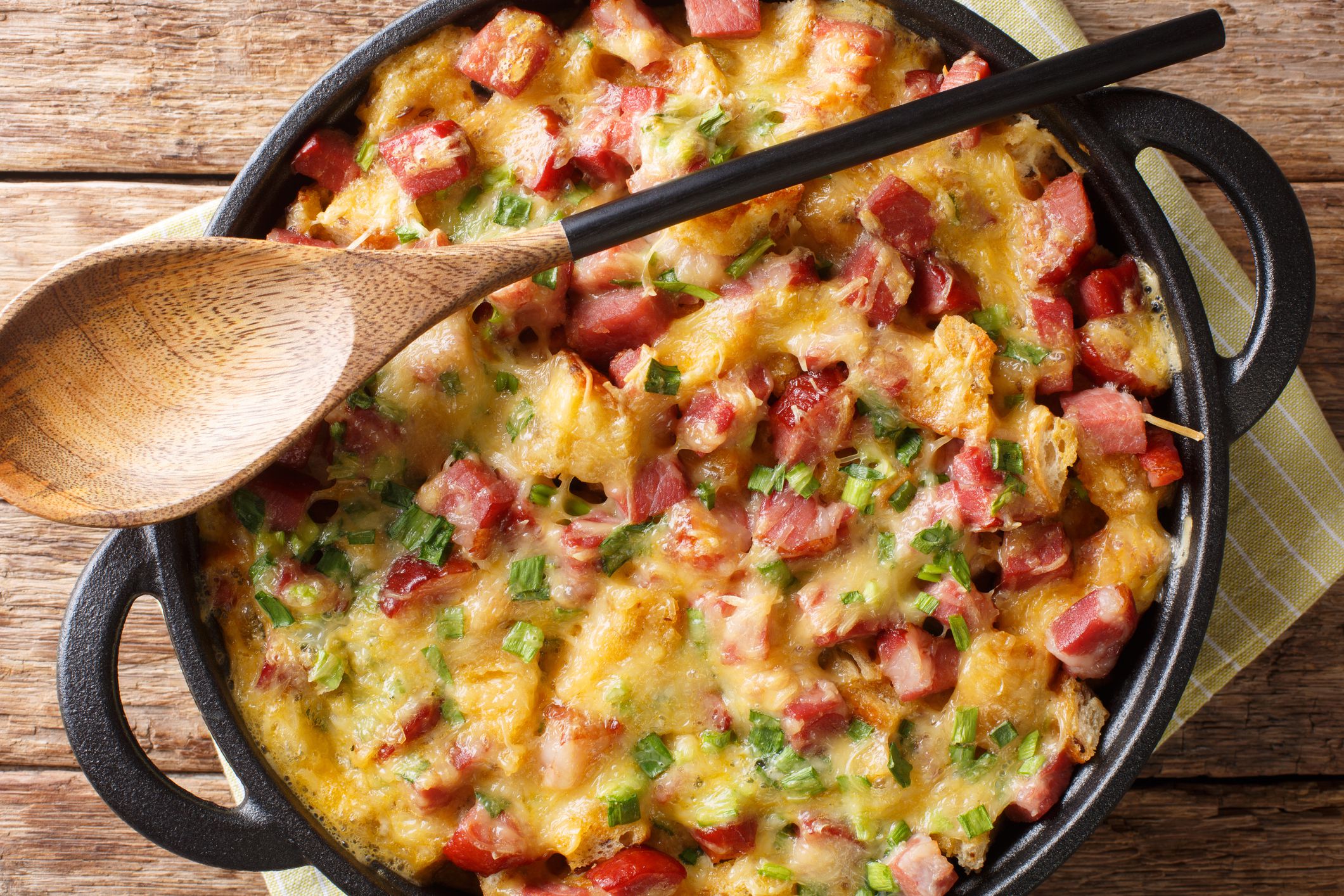 recipe for a simple strata with ham, bread, onions, cheese and eggs close-up in a pan on the table. Horizontal top view from above