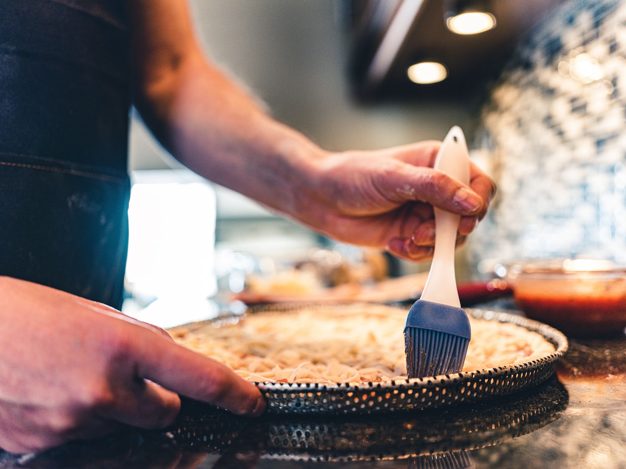 Close up of hands of Middle aged man making pizza at home kitchen