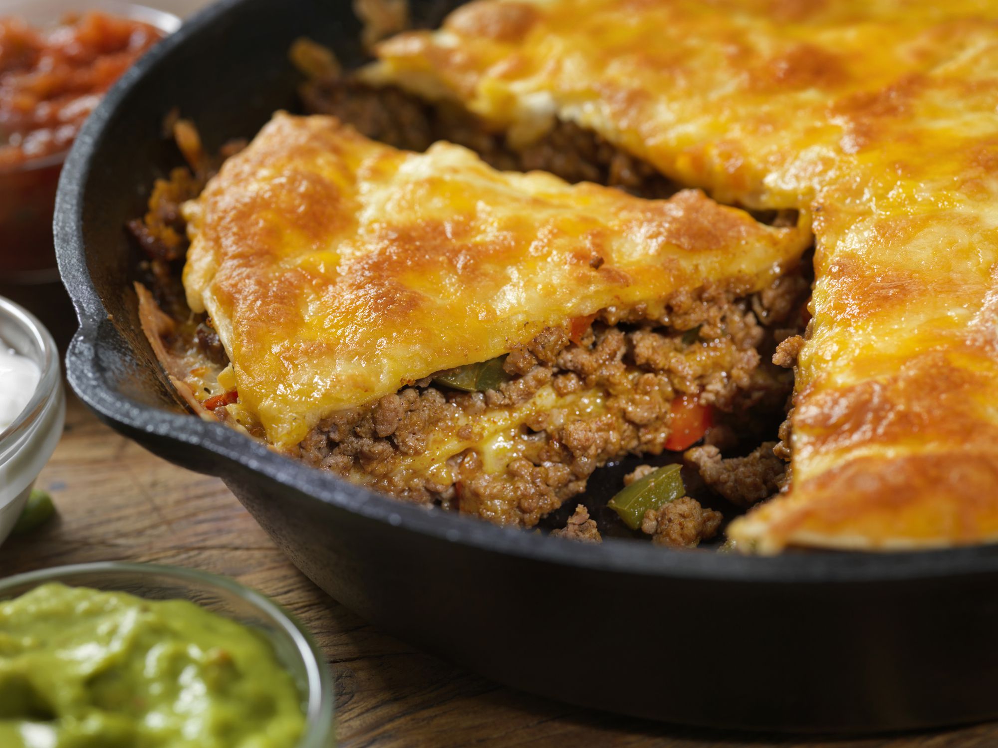 Layered, Beef Taco Pie Baked in a Cast Iron Skillet with Sour Cream, Salsa and Guacamole