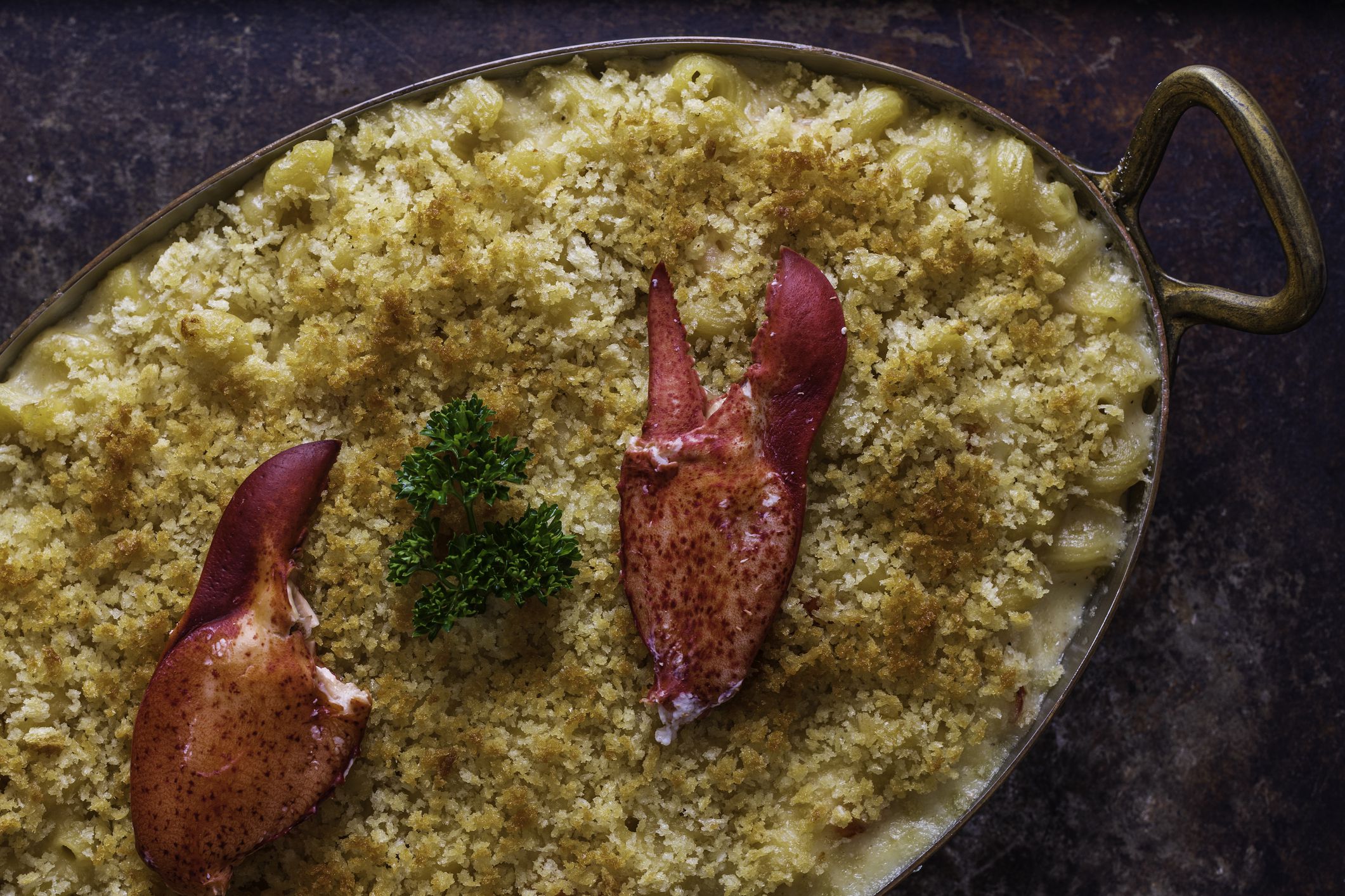 Baked mac and cheese with lobster and a bread-crumb crust. Garnished with parsley and lobster claws.