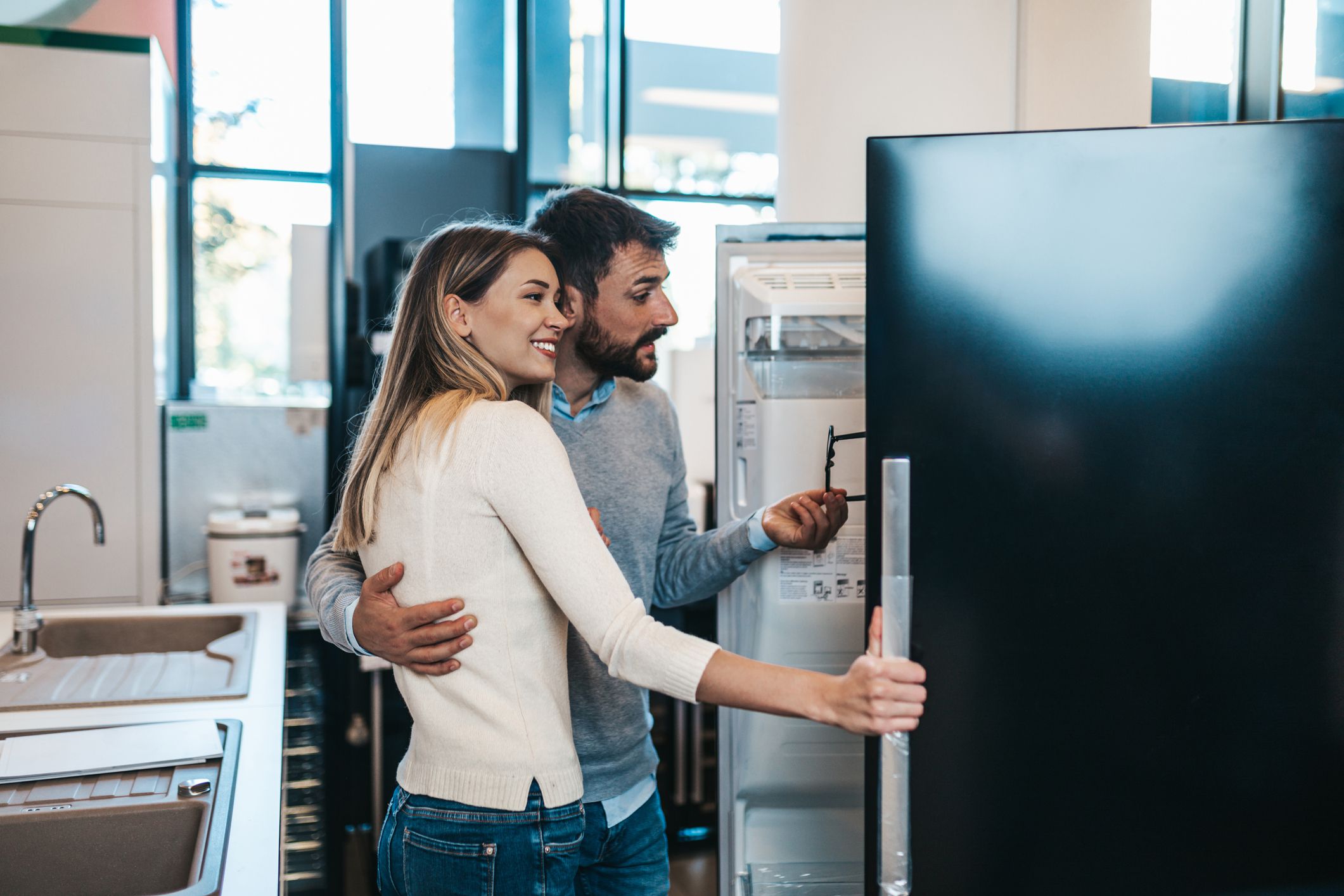 Happy young couple buying household appliances in store.