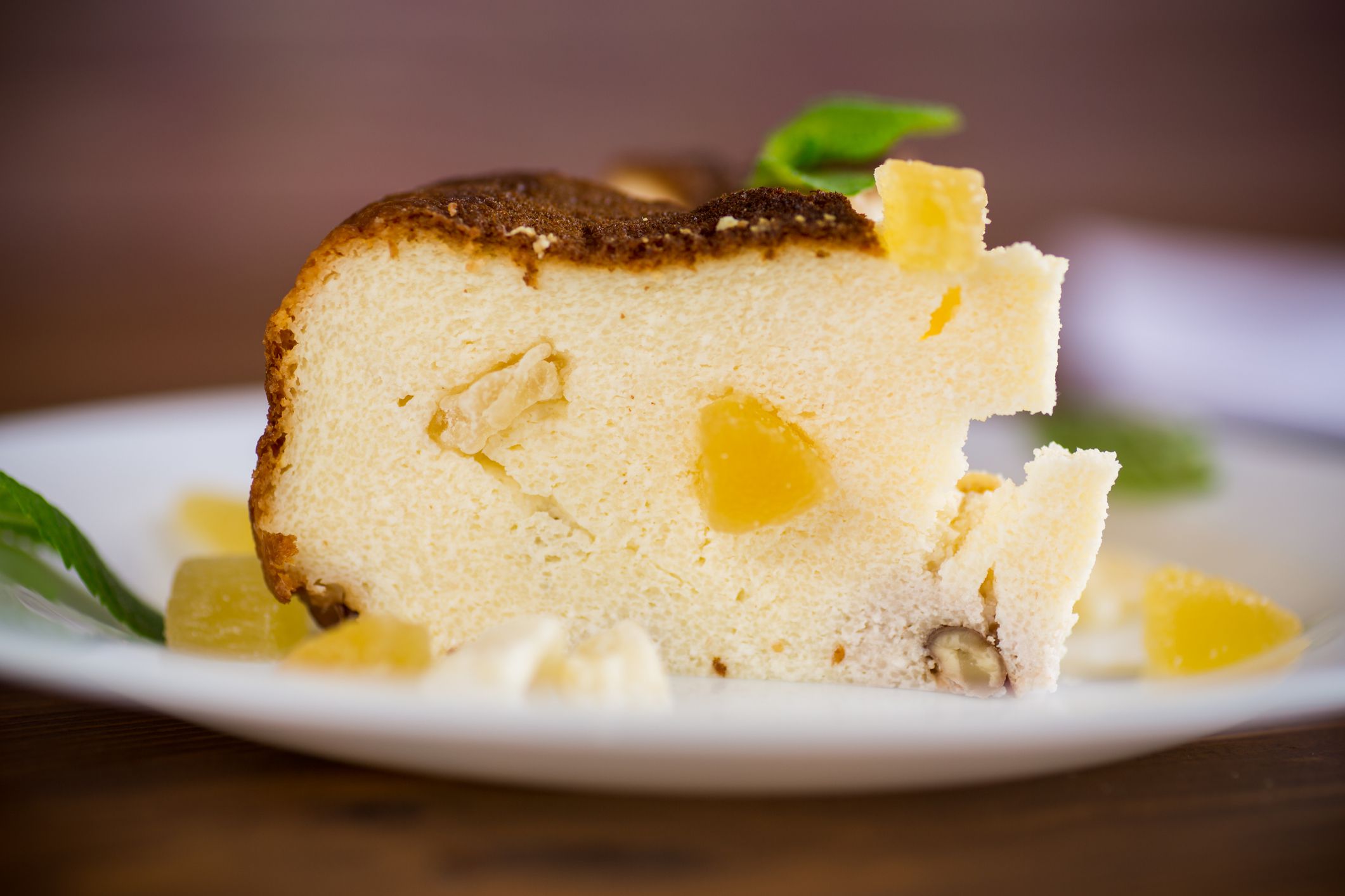 sweet baked cottage cheese casserole with nuts and candied fruits on a wooden table