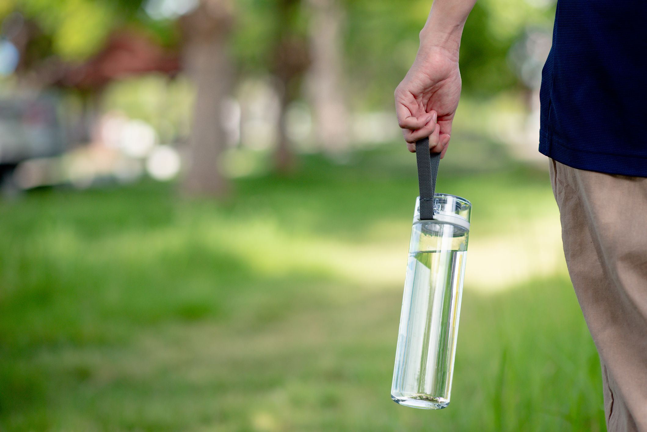 Hand holding a clean drinking water bottle. Plastic bottle of drinking water with green blurred background.