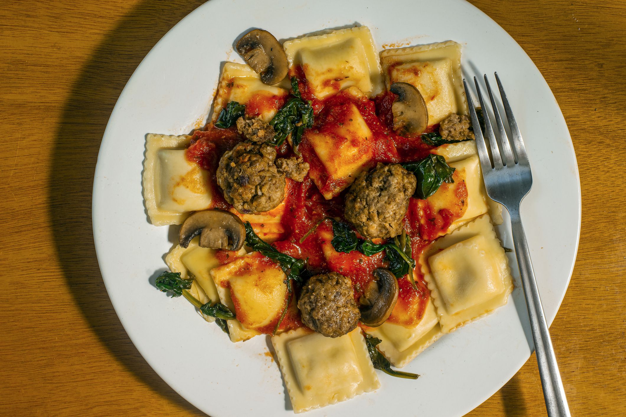 cheese ravioli served with sauteed spinach and mushrooms, with meatballs