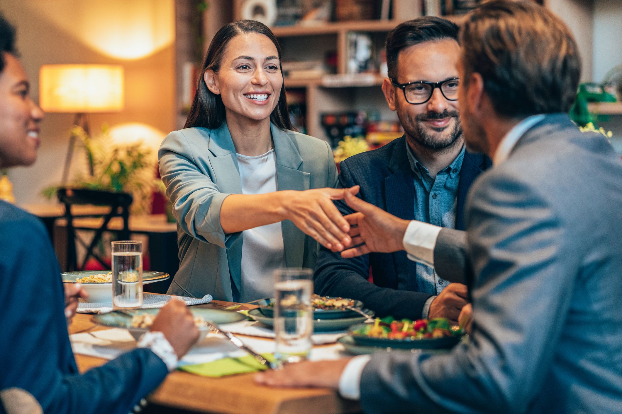 Businessman meeting colleagues with a handshake arriving at the restaurant. Business team having lunch together enjoying each other company. Business discussion and fun at the lunch break.
