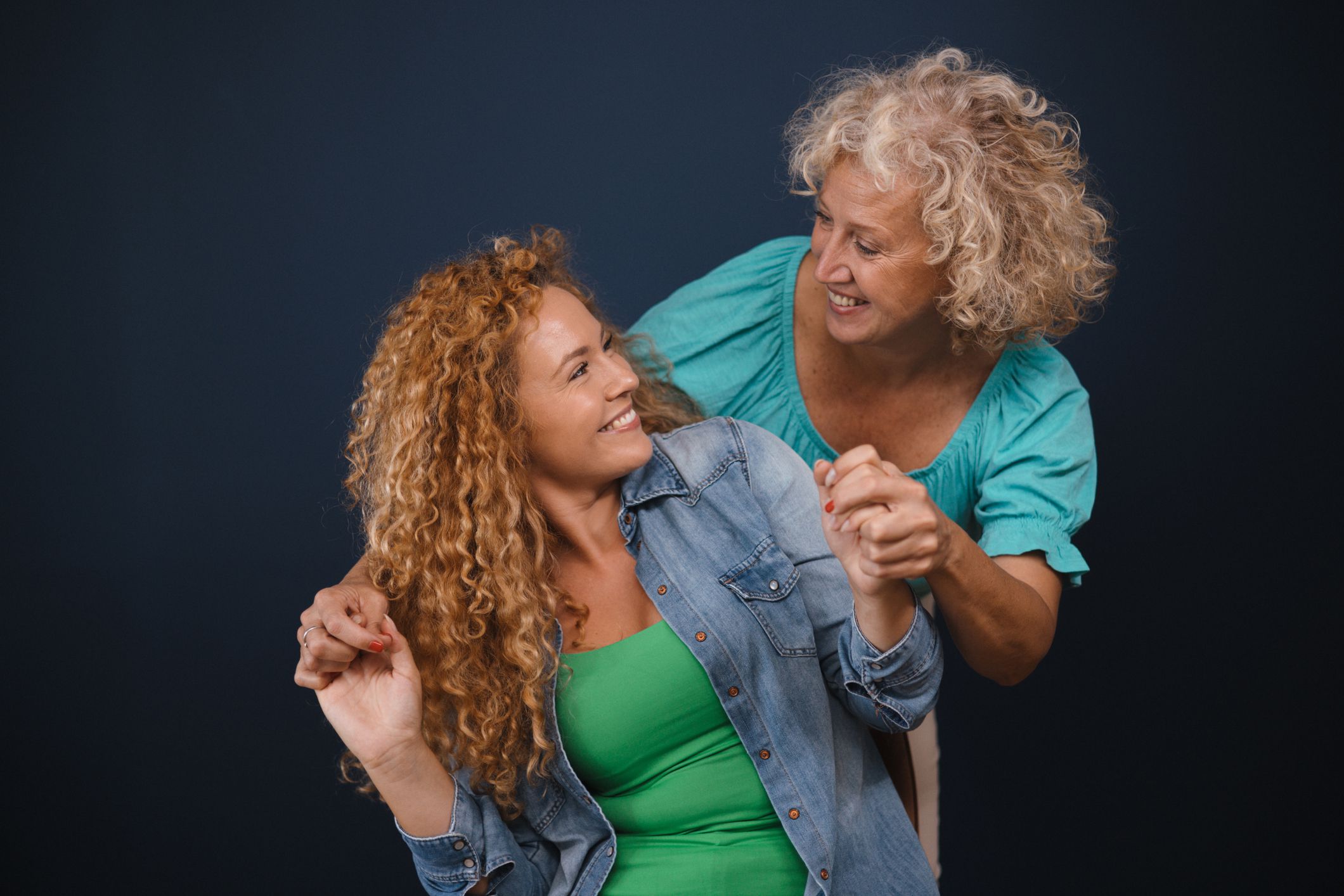 Mid adult blonde woman and redhead curly daughter having a great time together