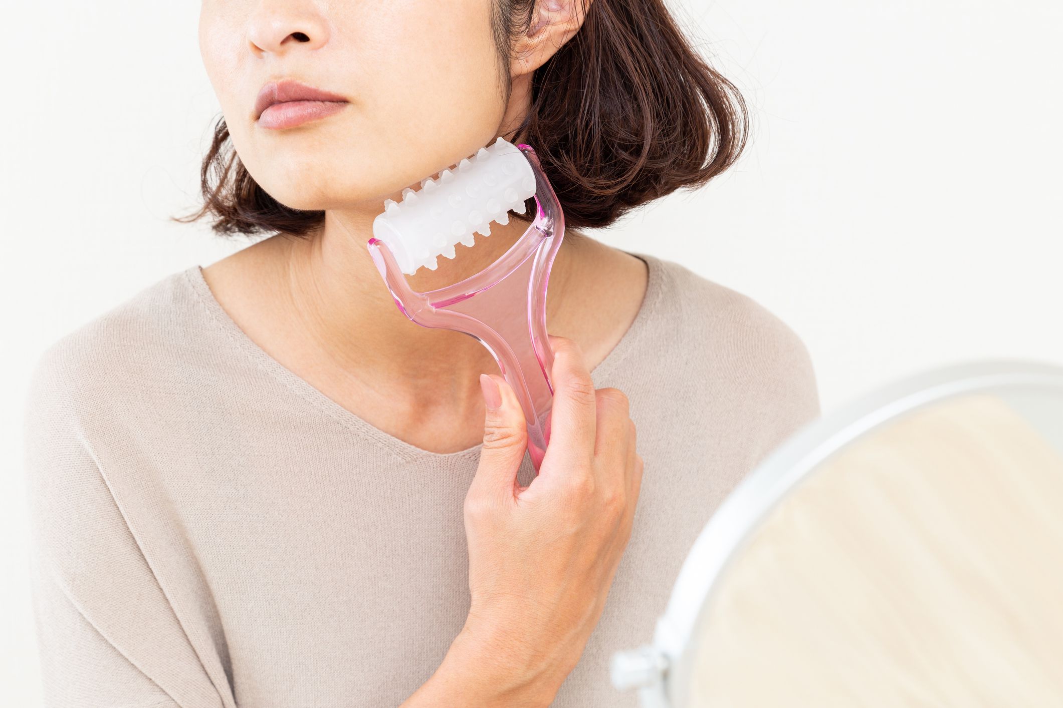 A woman using a facial roller.