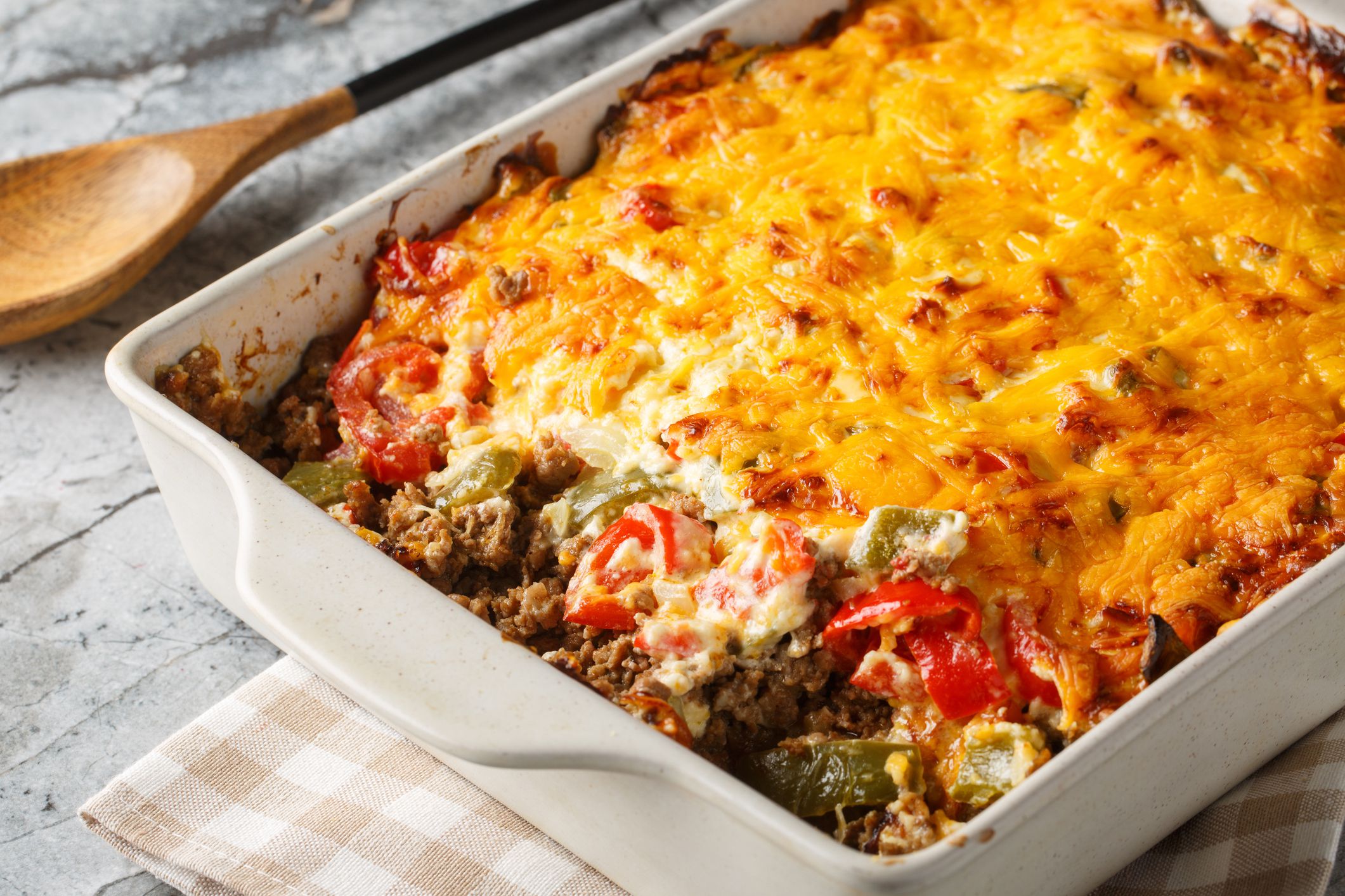 Casserole layers of ground beef, cheese, fresh vegetables and Jalapeno peppers baked closeup on the baking dish on the table. Horizontal
