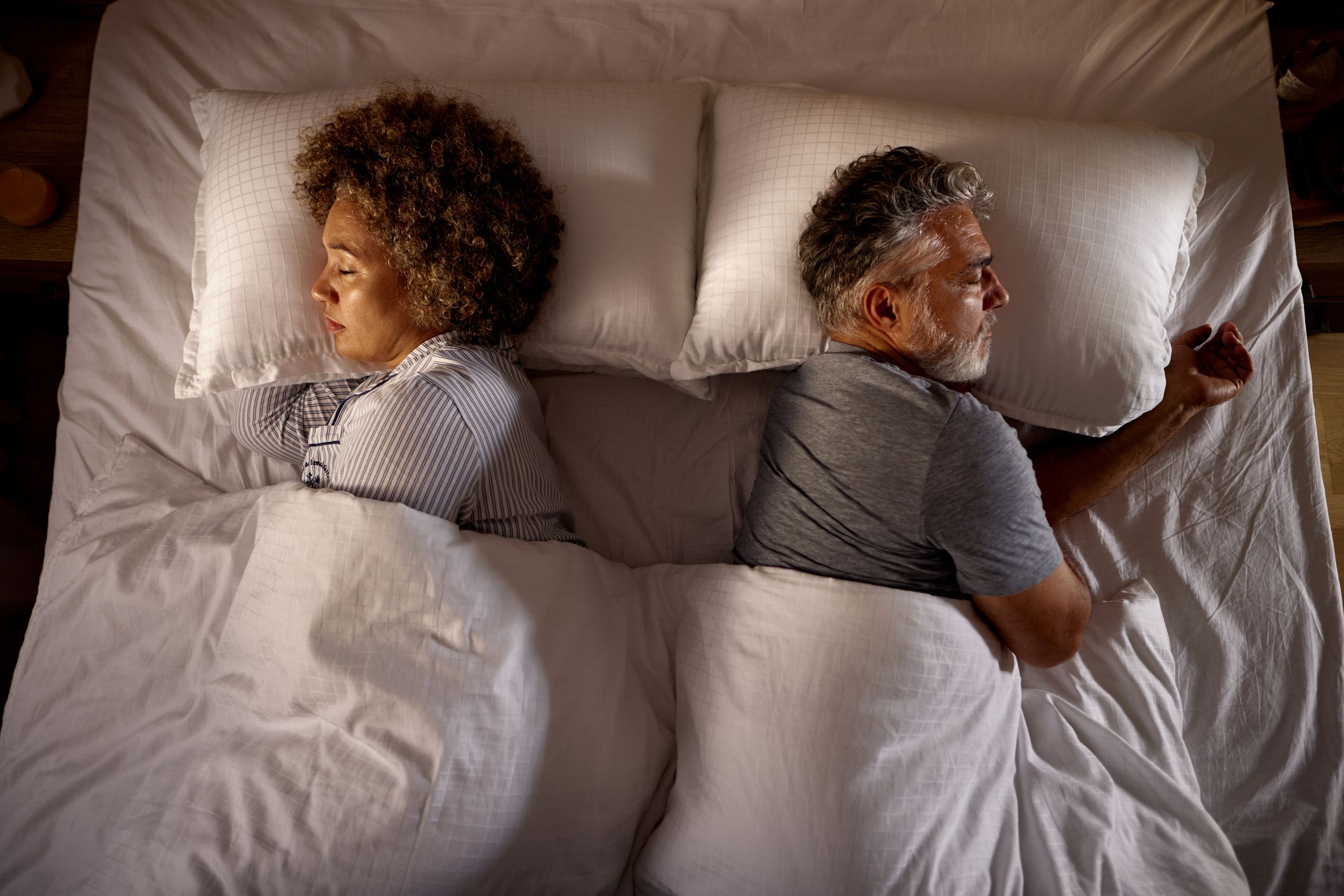 High angle view of relaxed senior couple sleeping back to back in a bed.