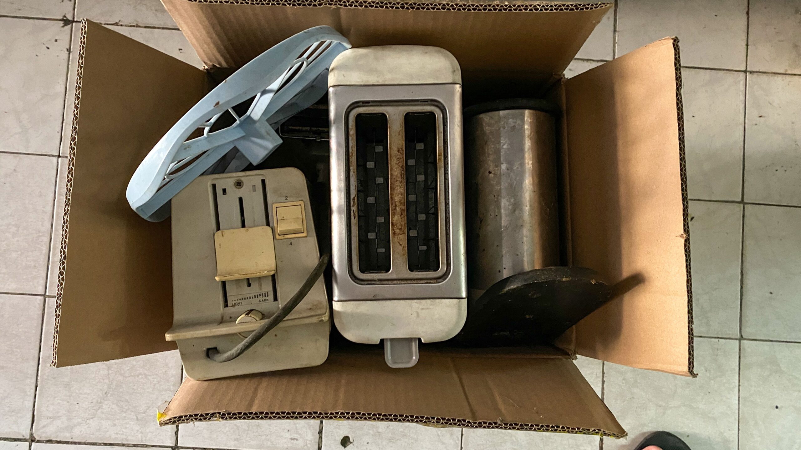 Throw away old kitchen appliances. Disposal of electrical appliances in the card box. Find it in the trash. Throw the bread toaster in the trash.