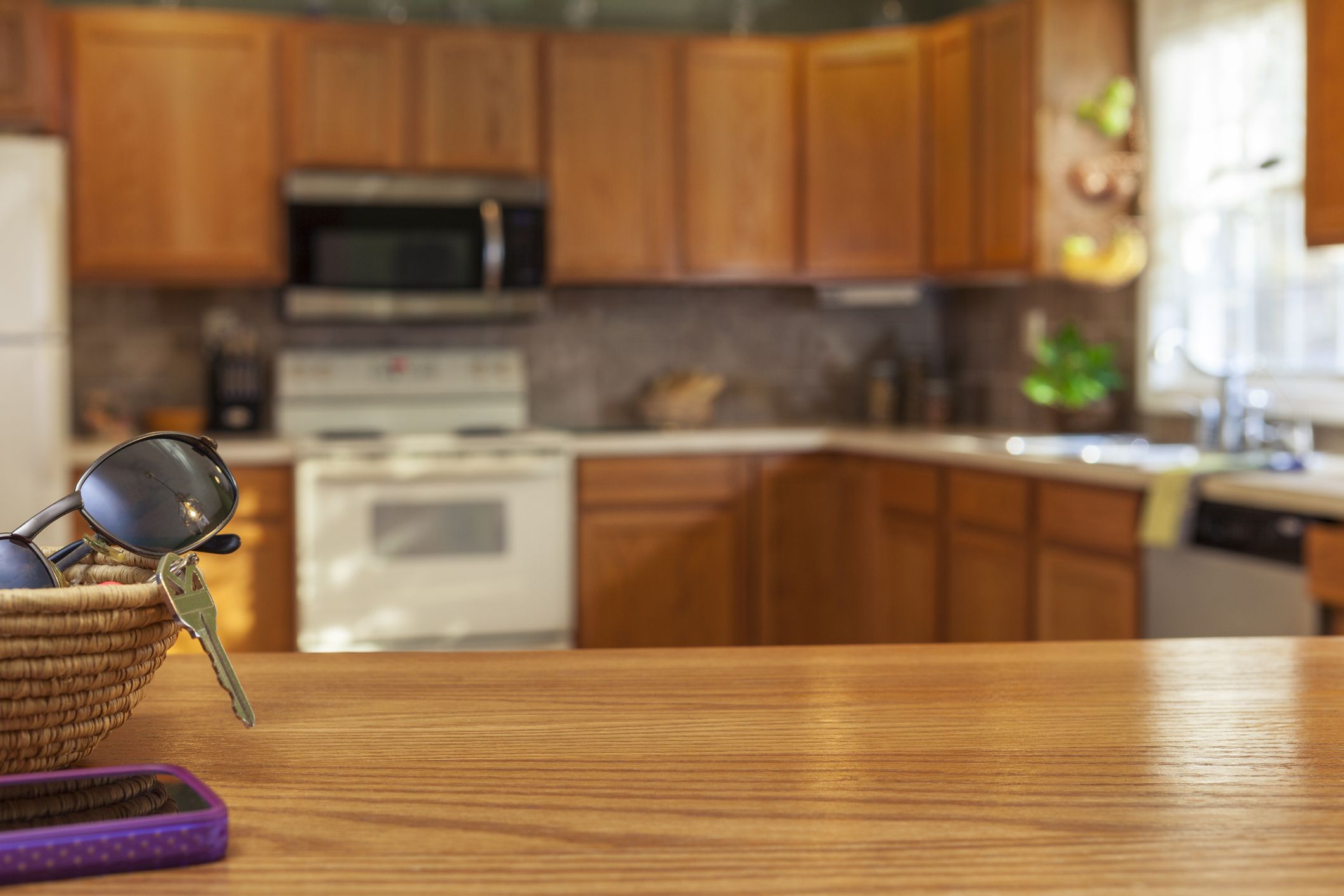 Kitchen interiors, showing table top, oak cabinets, sink, stove and tiled backsplash.