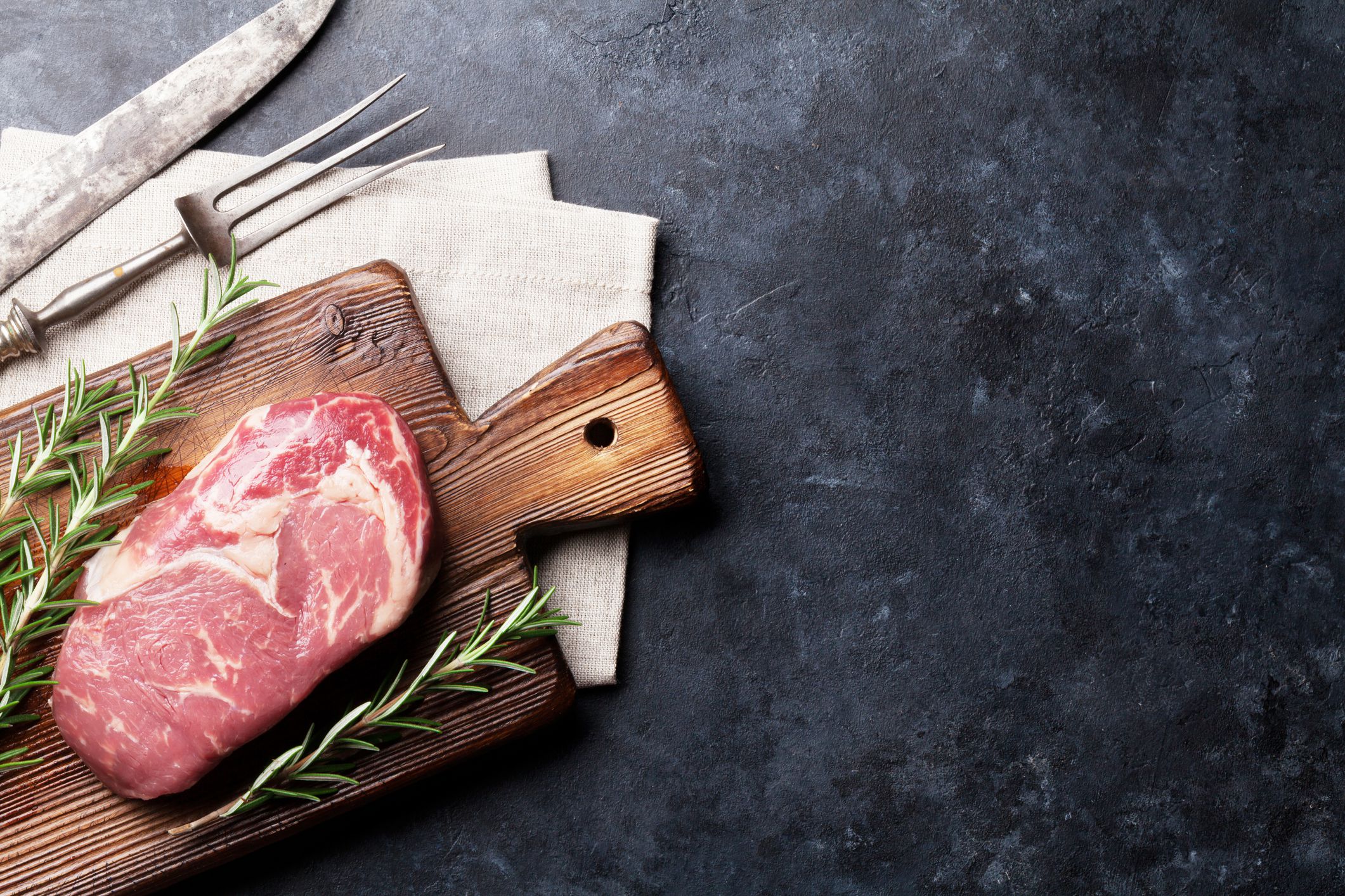 Raw beef steak cooking and ingredients. Meat piece, herbs and spices. Top view with copy space over stone table