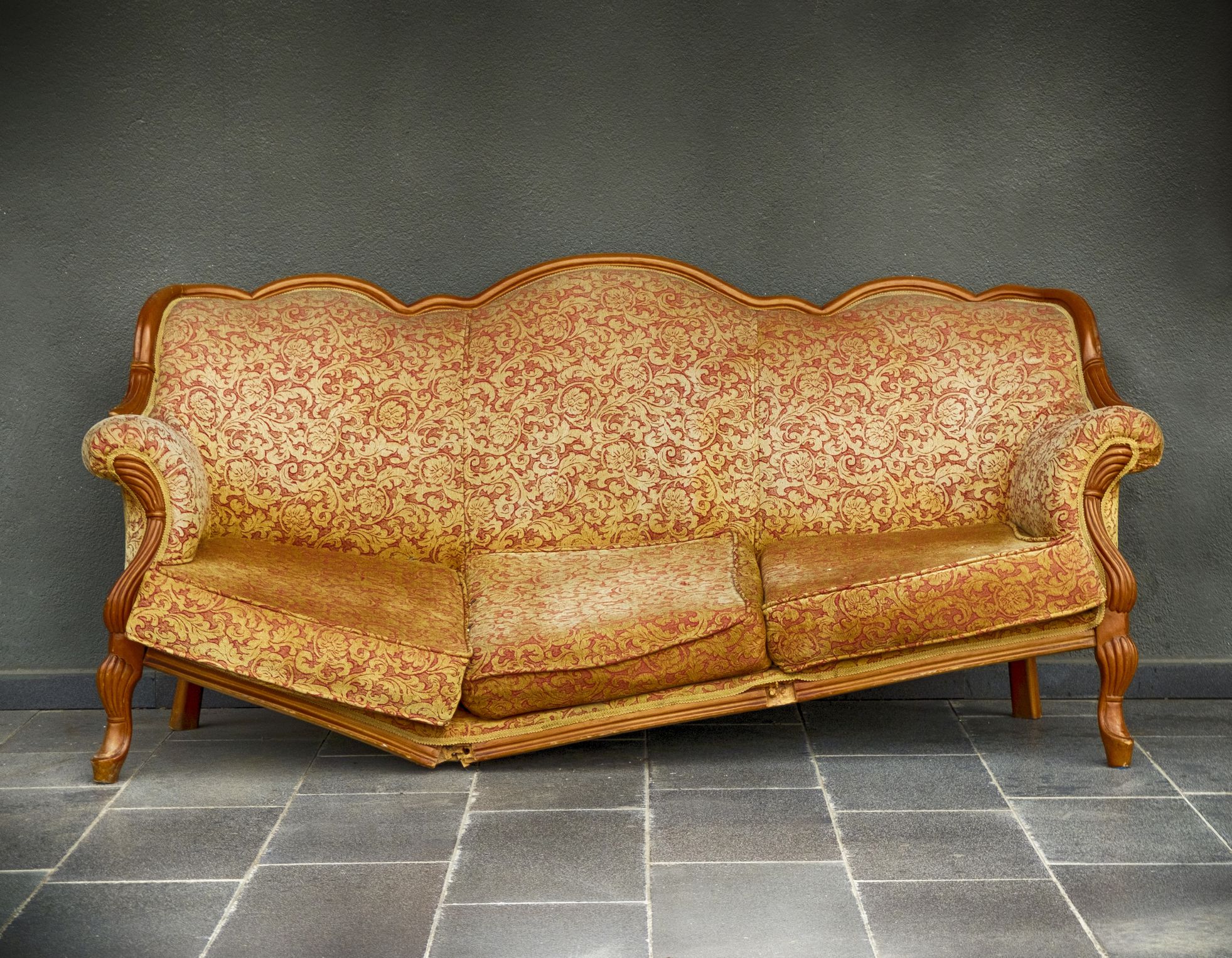 A broken armchair which is standing in front of the wall.