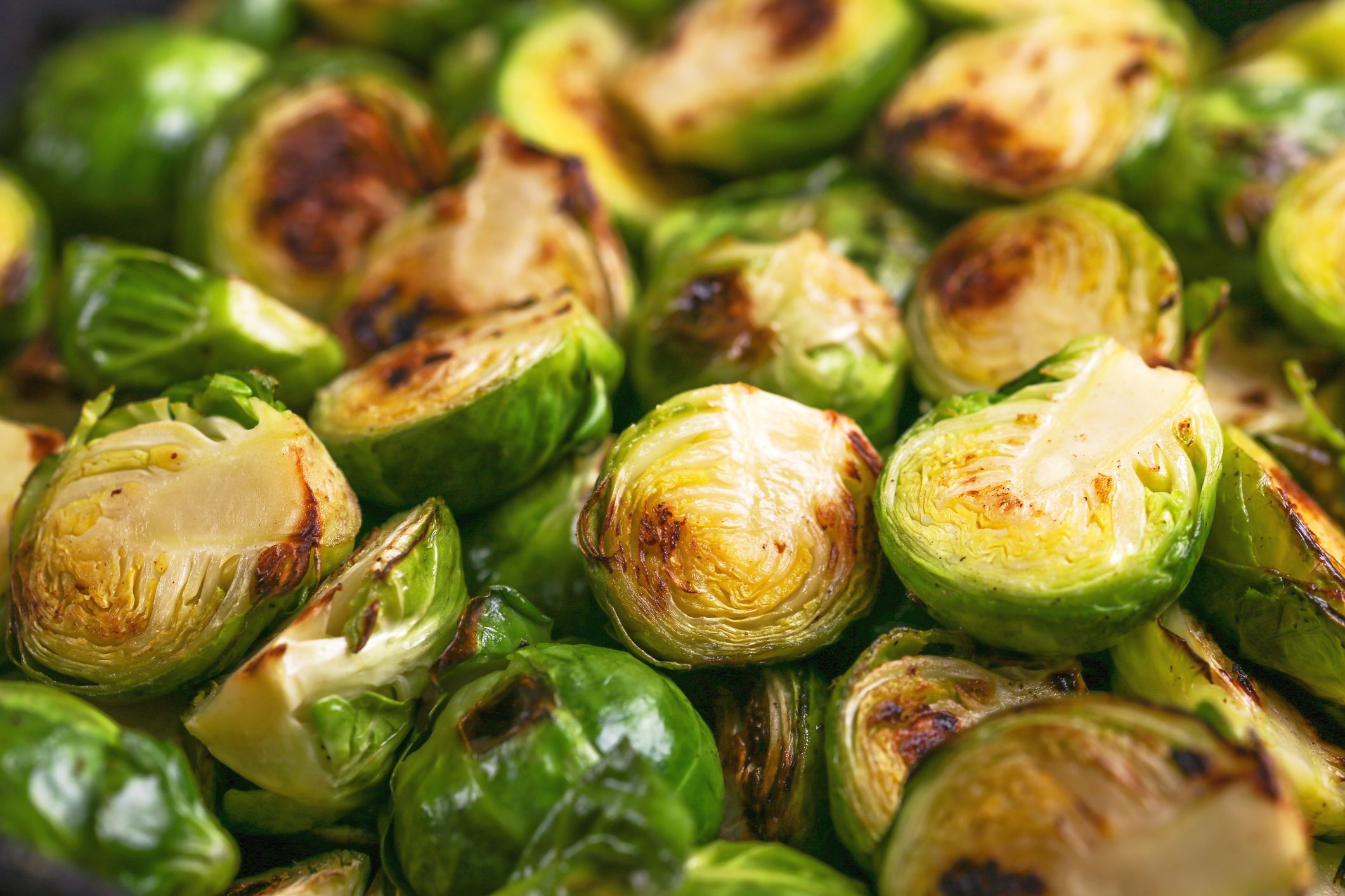 Vegetarian cuisine. Homemade Brussels Sprouts roasted with olive oil on black slate background. Copyspace, top view, flatlay.