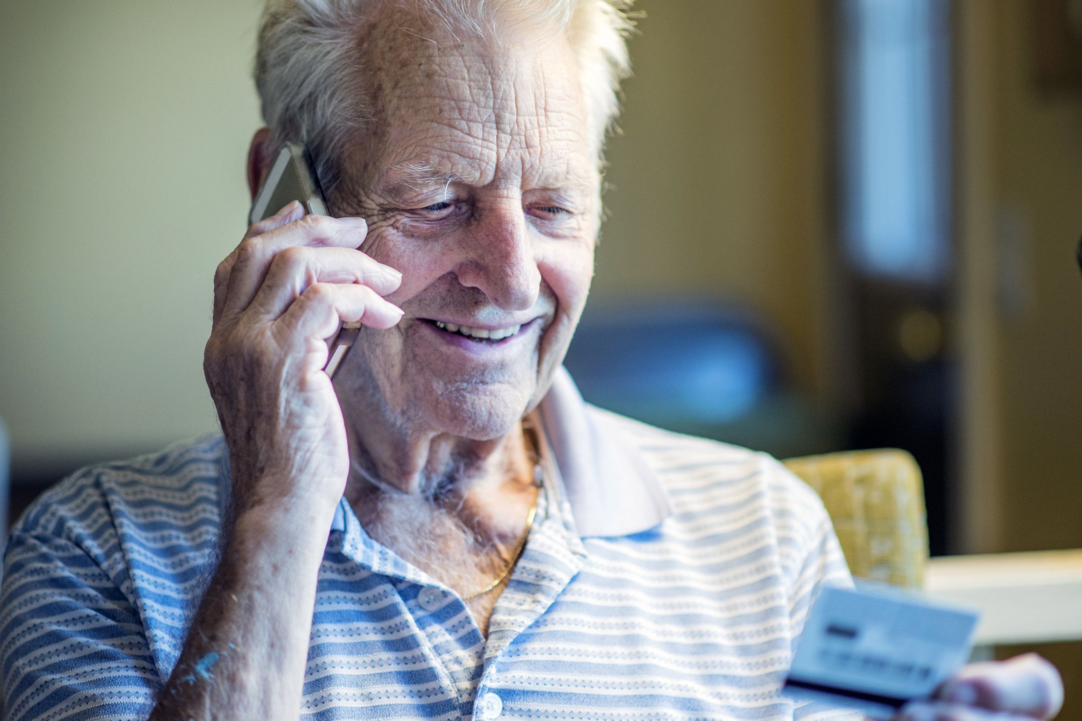 man looking at credit card smiling with phone to ear