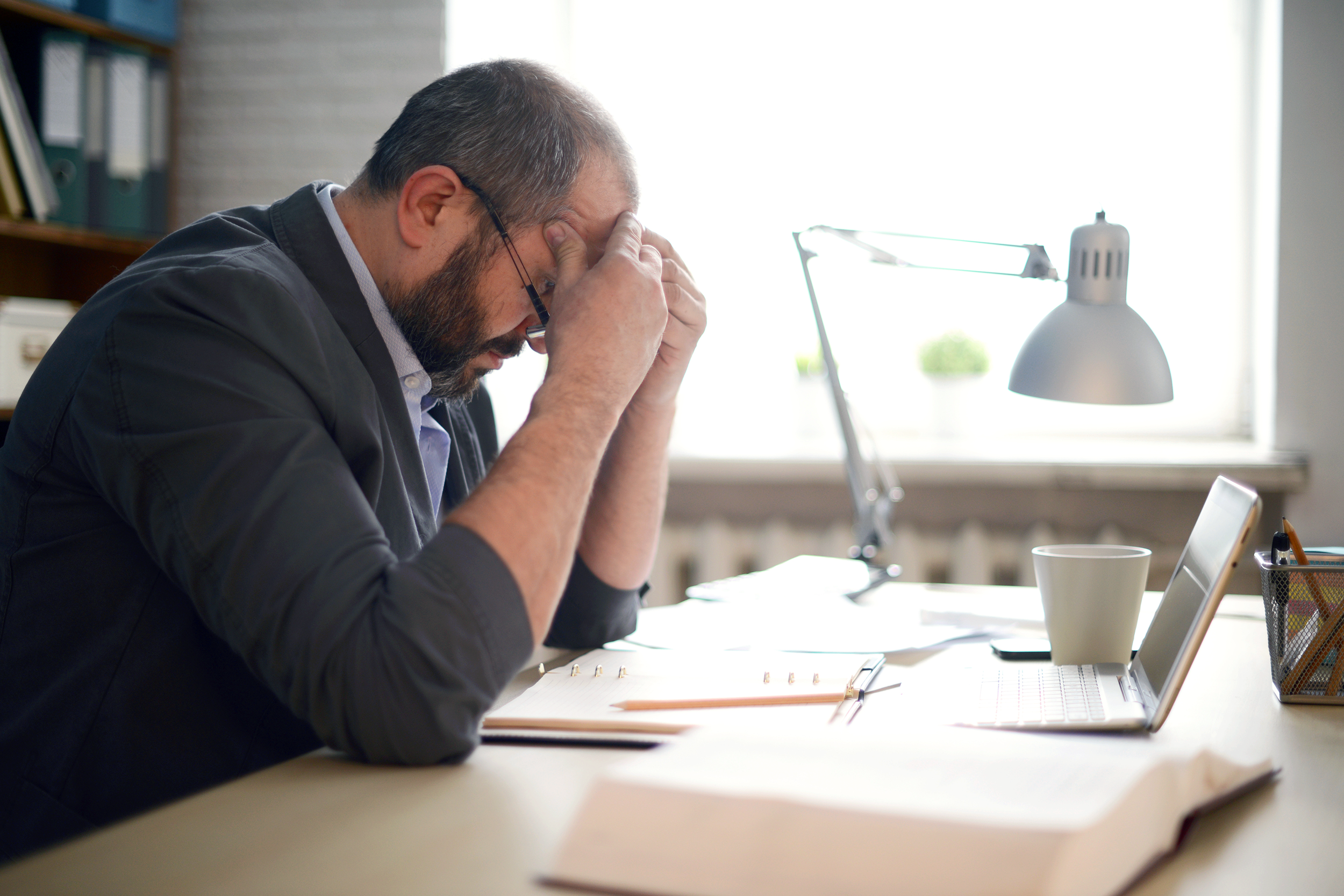 Stressed man sitting at his desk with his head in his hands