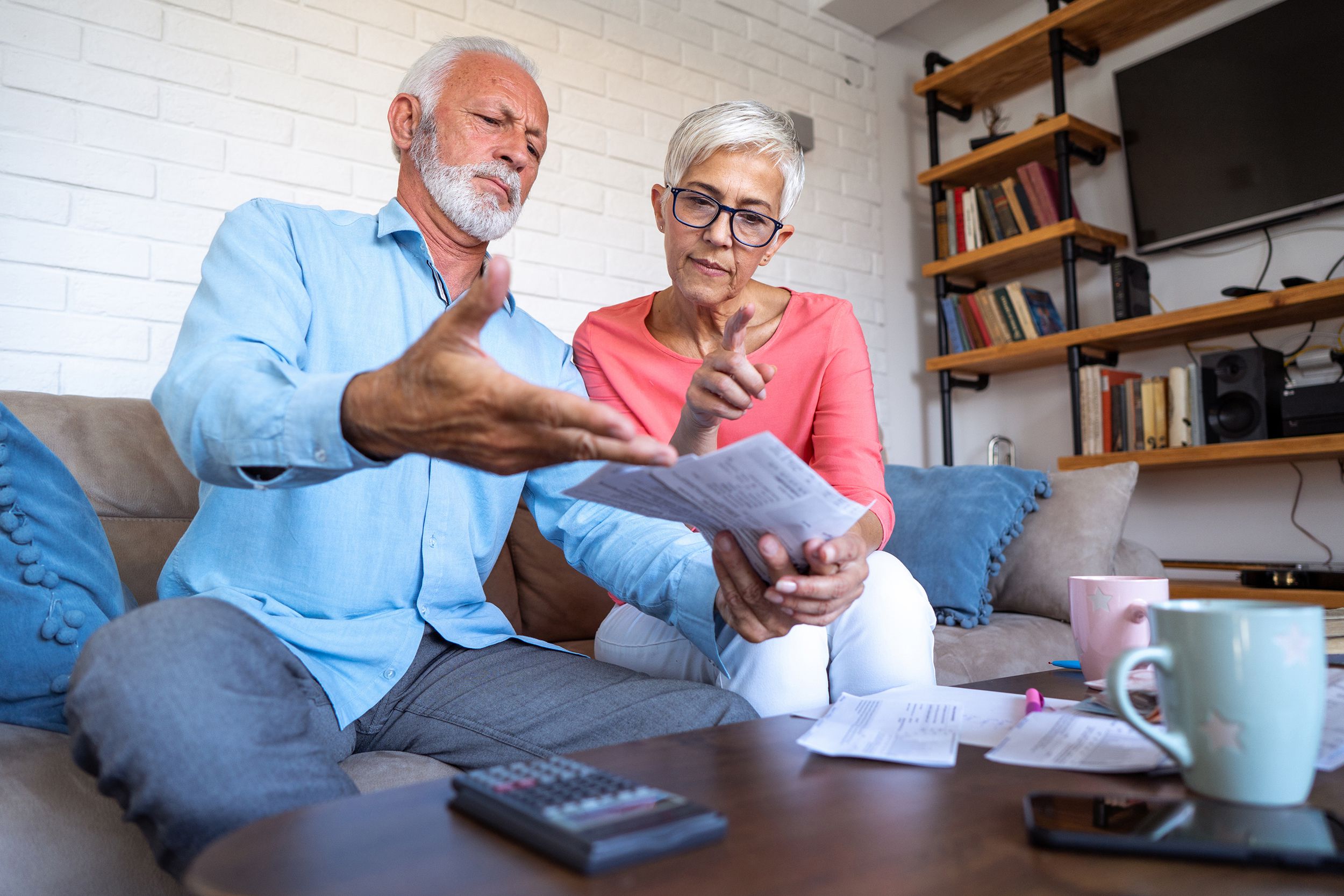 worried senior couple counting bills at home