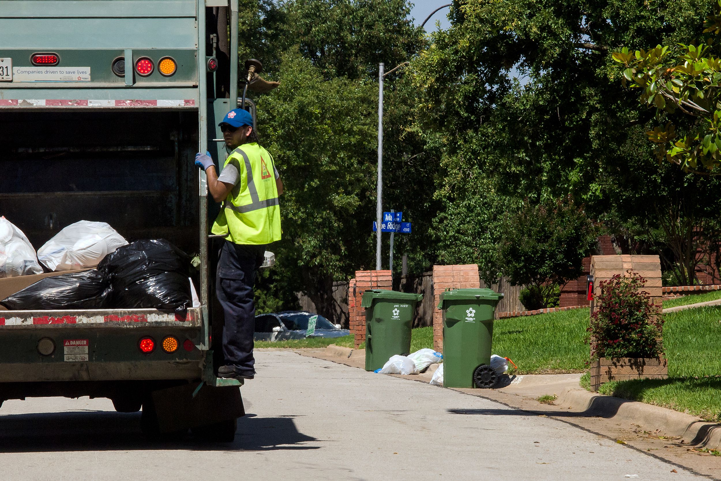 garbage truck with sanitation worker in suburbian neighborhood