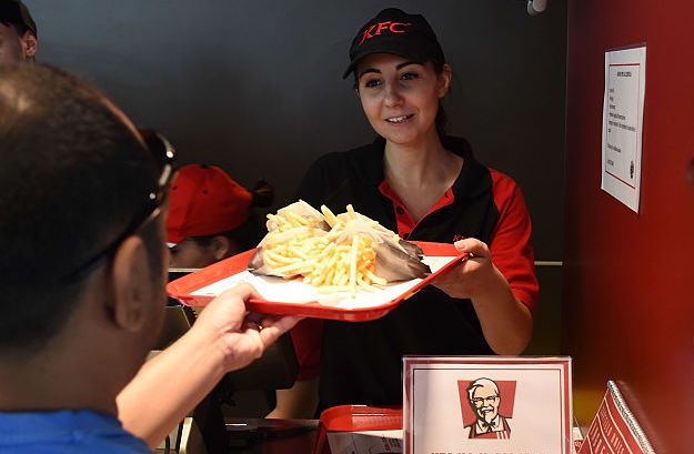 An employee handles a tray of food during the opening of a new Kentucky Fried Chicken branch on July 28, 2016 in Milan, Italy.
