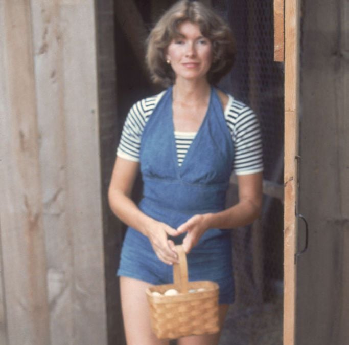 American media mogul and businesswoman Martha Stewart exits a chicken coop with a basket of eggs, August 1976.