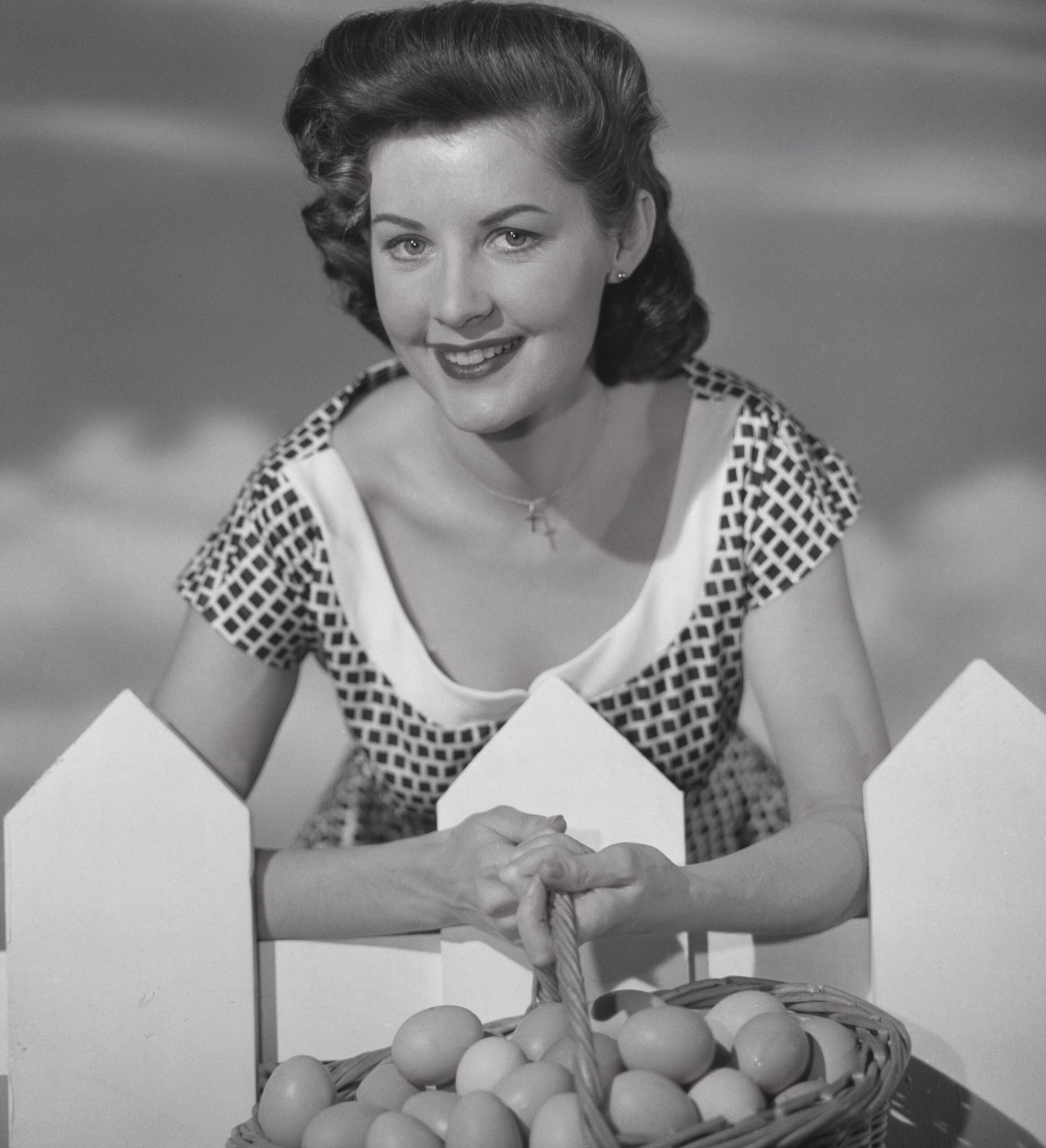 A young woman holding a basket of eggs, circa 1955.