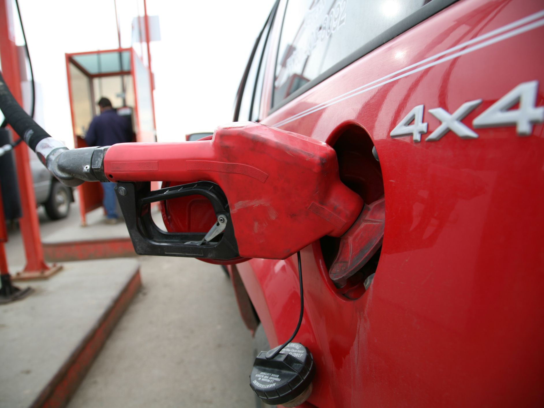 A red truck filling up at a gas station