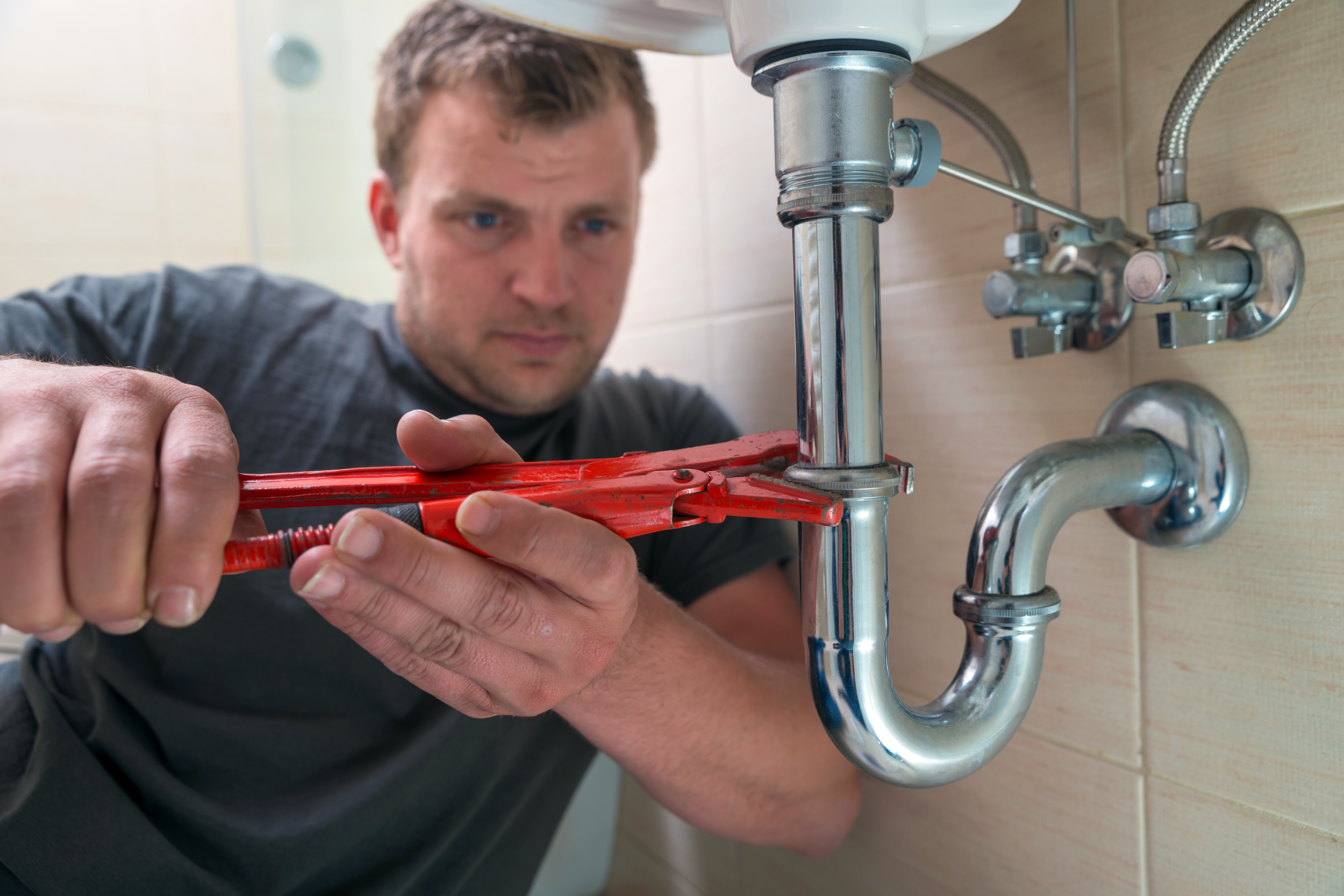 Man fixing a pipe under a sink