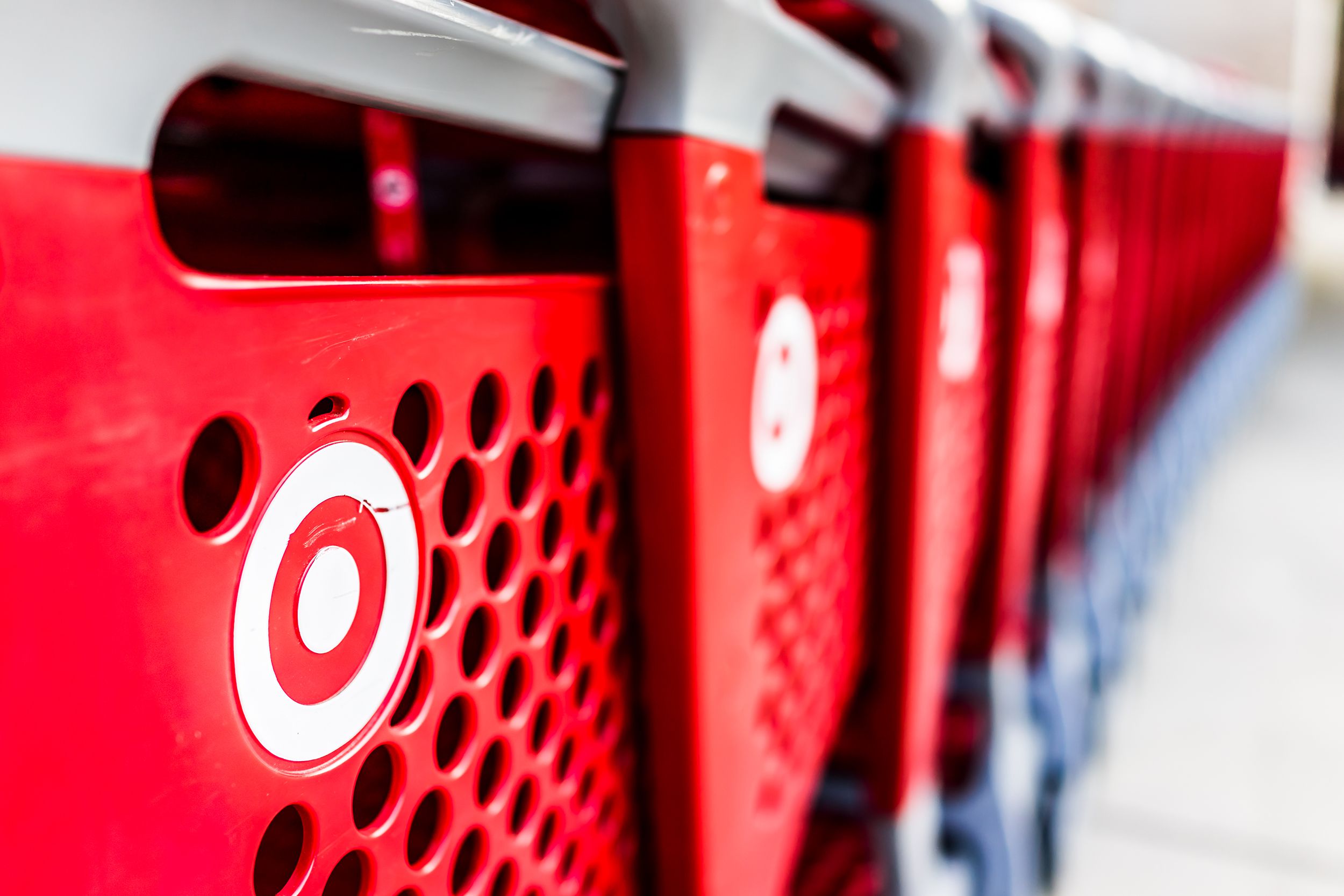 A row of red plastic Target shopping carts outside a Target store, selective focus of left, gradient blur to the right
