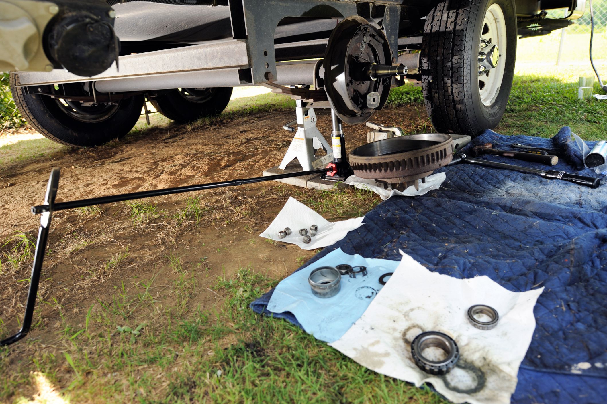Servicing the bearings and brakes on a RV, underneath of the RV, wheel is off, outside on lawn