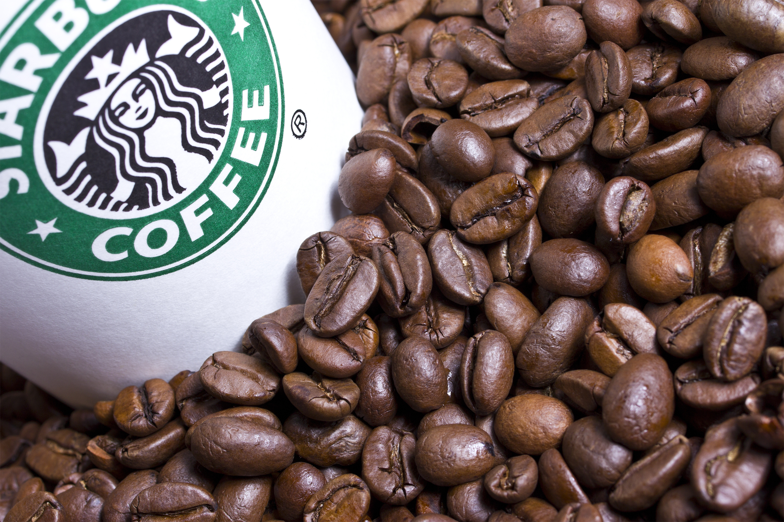 Starbucks coffee cup in pile of coffee beans
