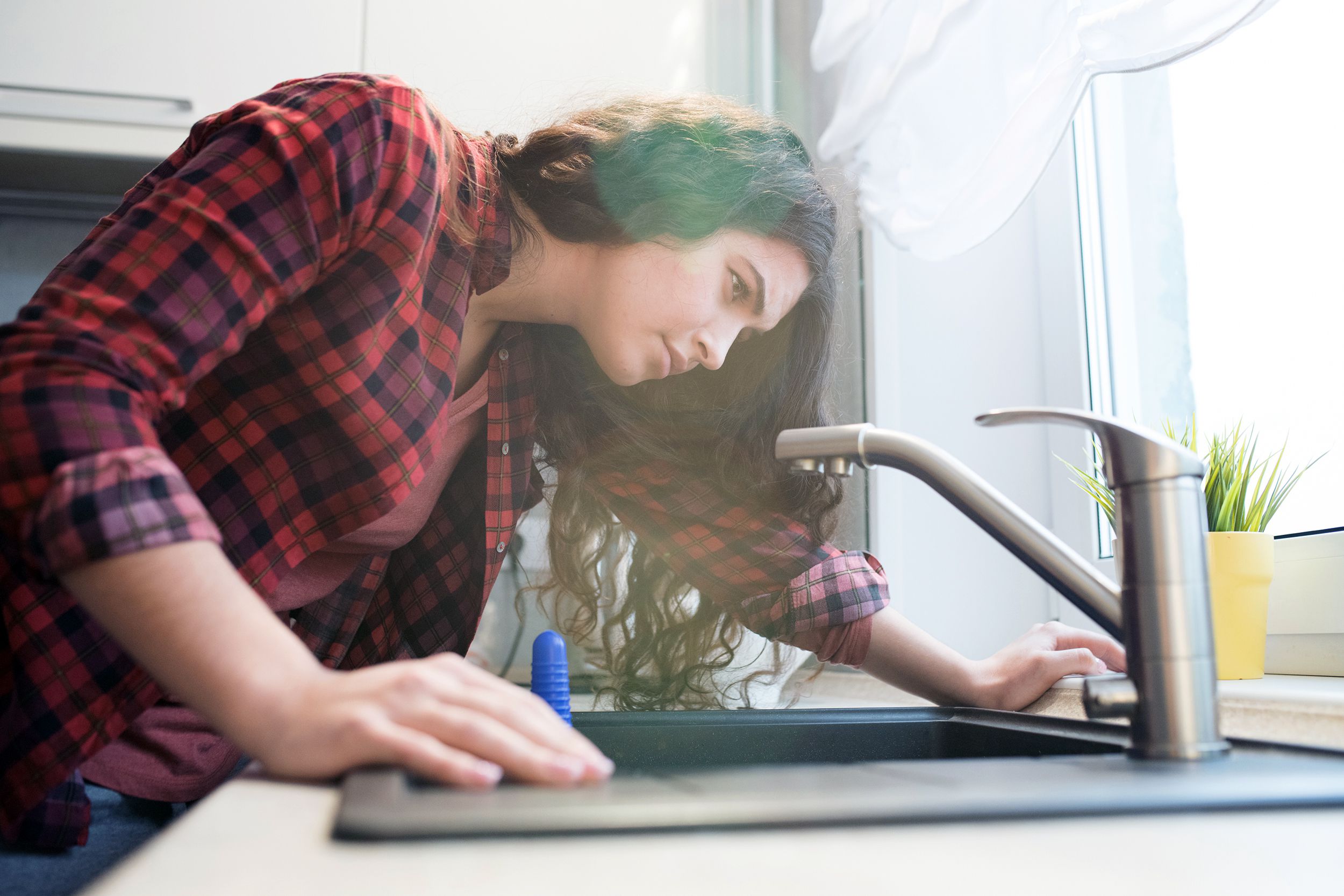 woman looking at faucet to figure out how to repair it
