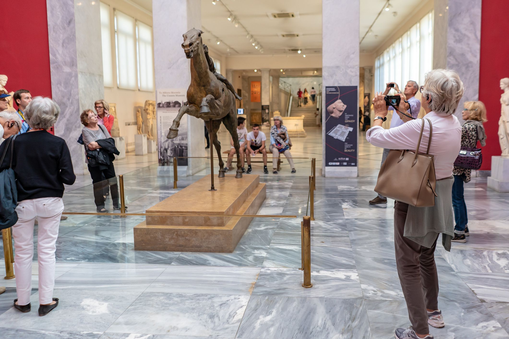 Athens, Greece - October 19, 2018: A tourist takes a photo of the famous Jockey of Artemision sculpture created in 150 B.C.
