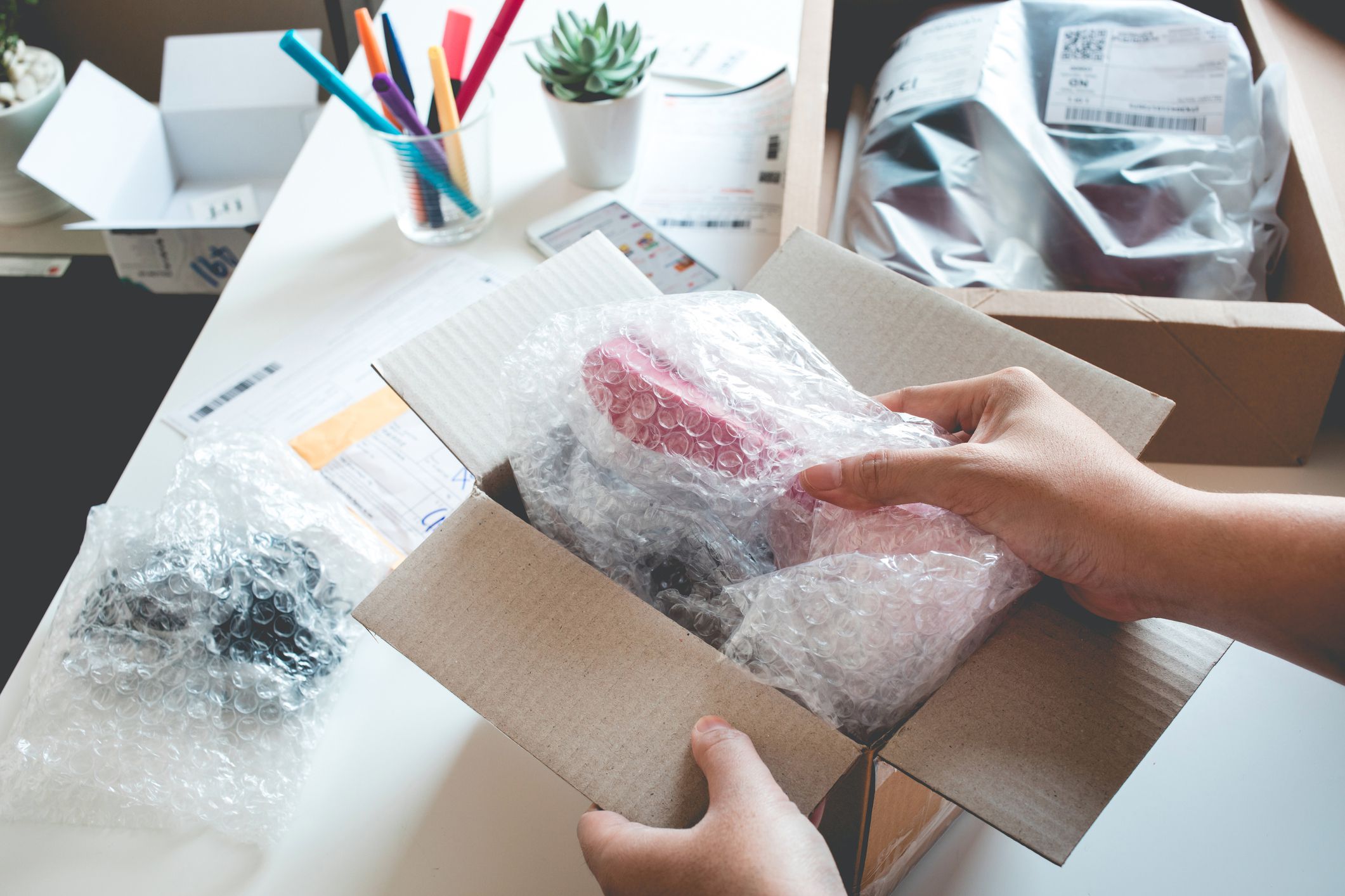 hands packing item into box with bubble wrap