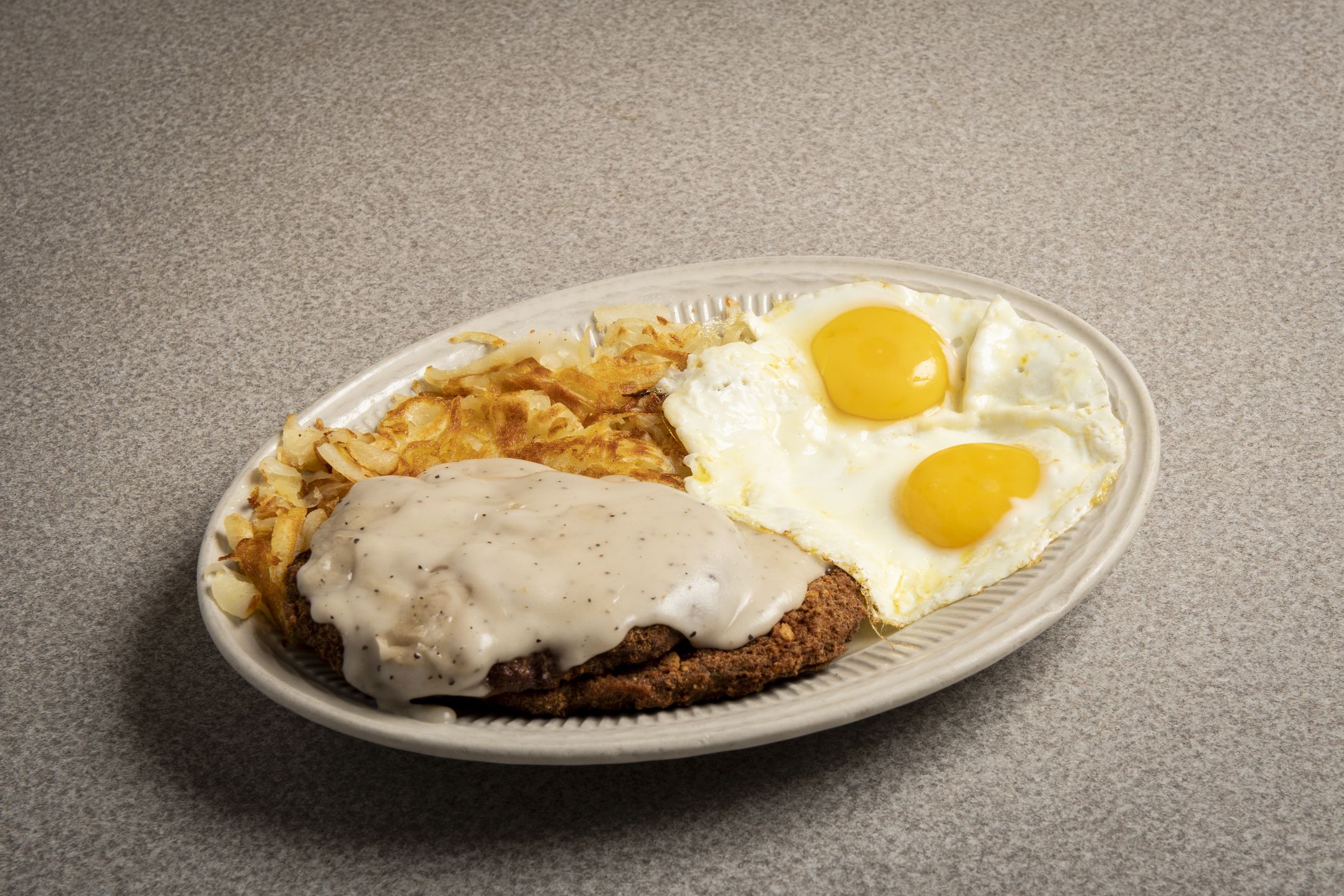 plate of chicken fried steak with eggs and hash browns