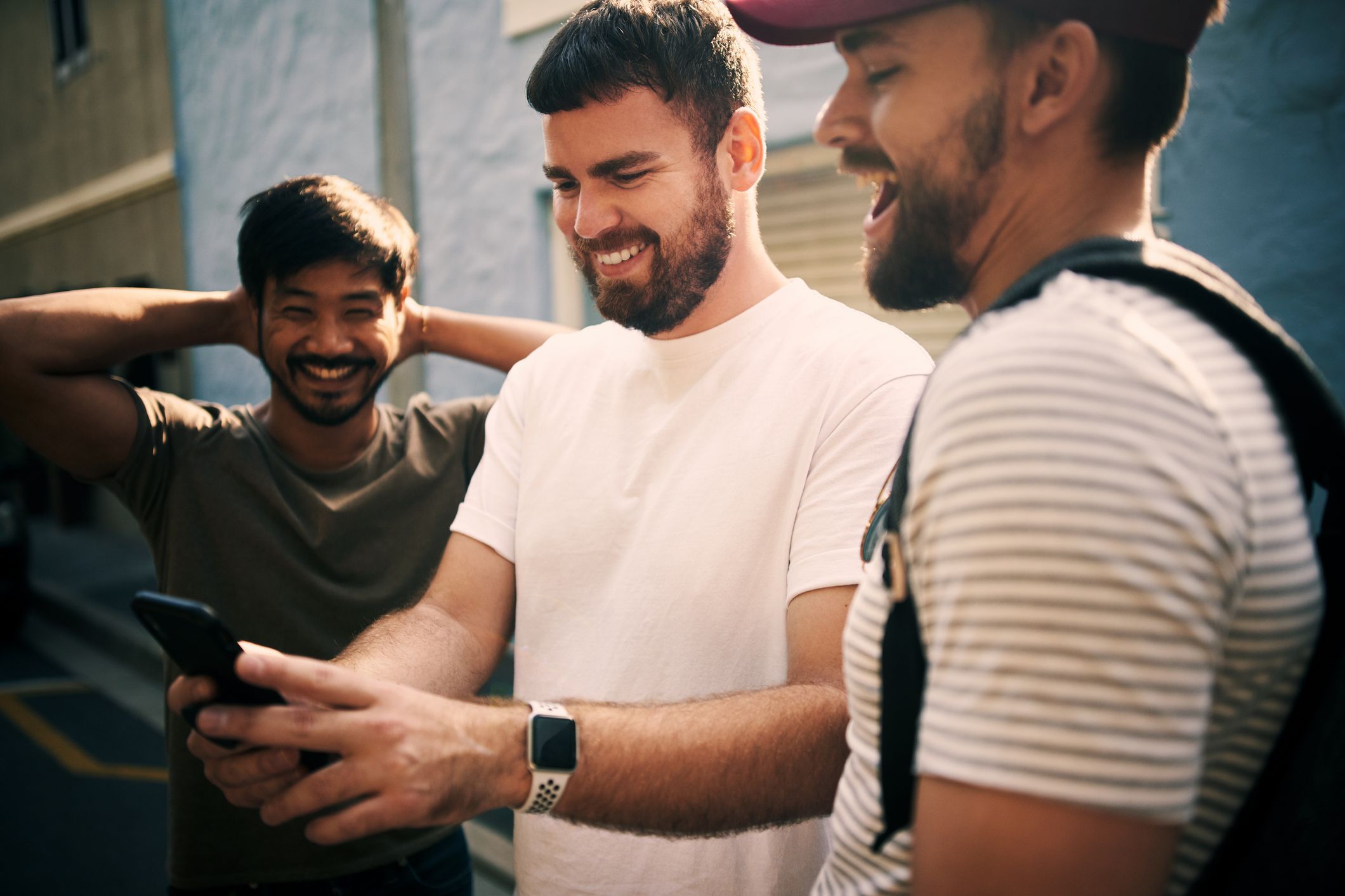 Cropped shot of three handsome young men standing together and using a cellphone while in the city during the day