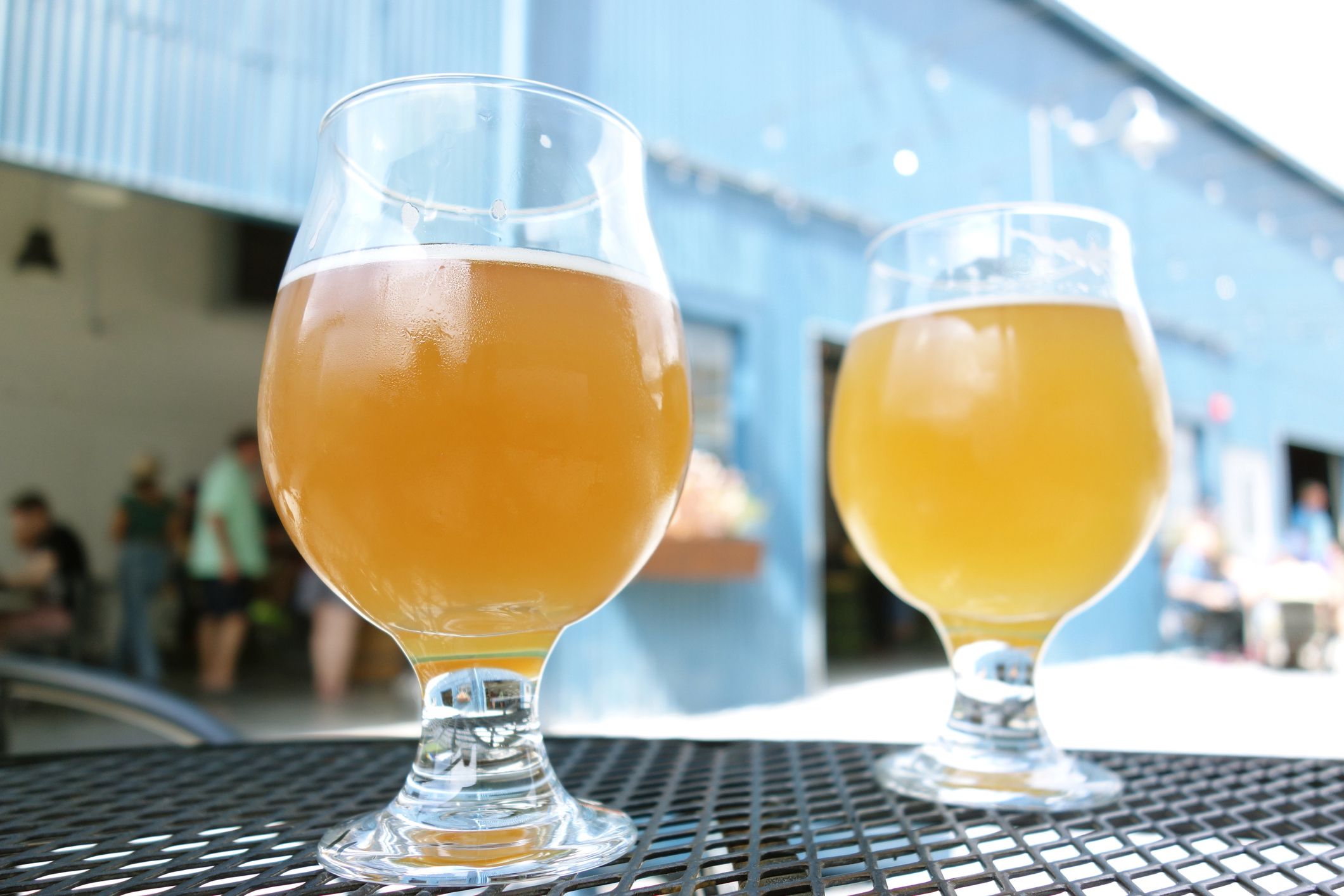 Two craft beer pints at a microbrewery in an outdoor courtyard table