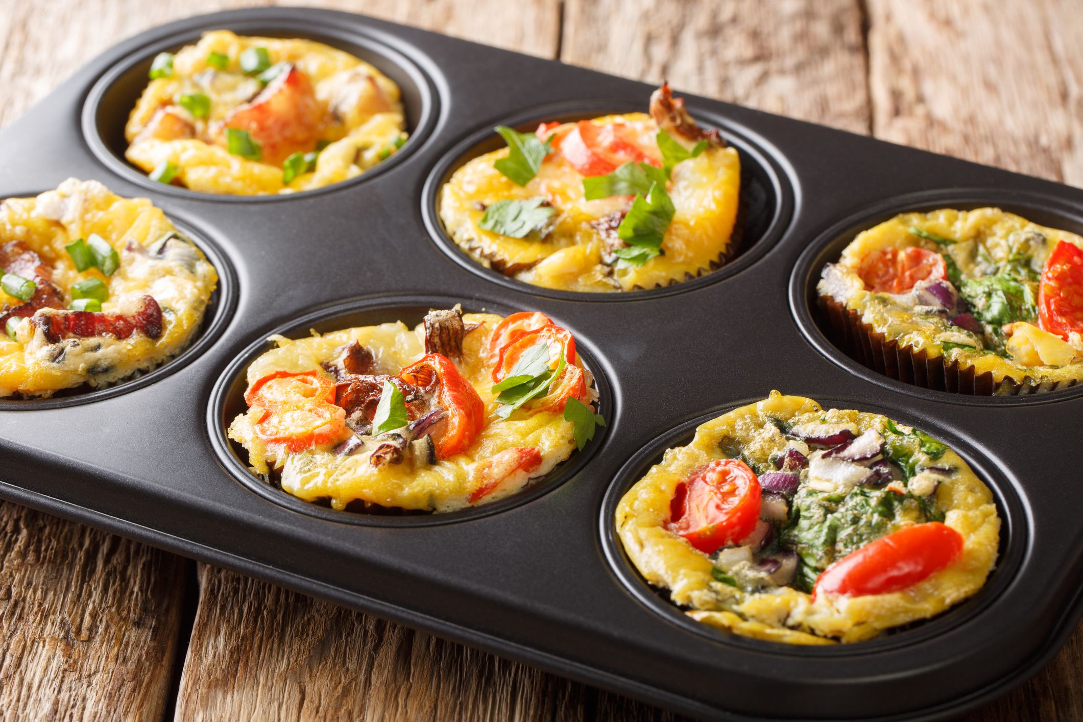 Frittata in the form of egg muffins with vegetables, cheese, bacon and mushrooms close-up in a baking dish on the table. horizontal