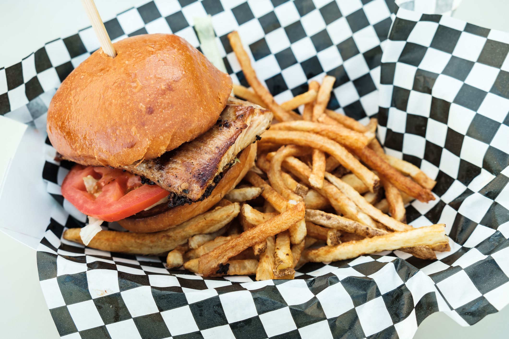 Blackened dolphin fish sandwich served with crispy french fried potatoes.