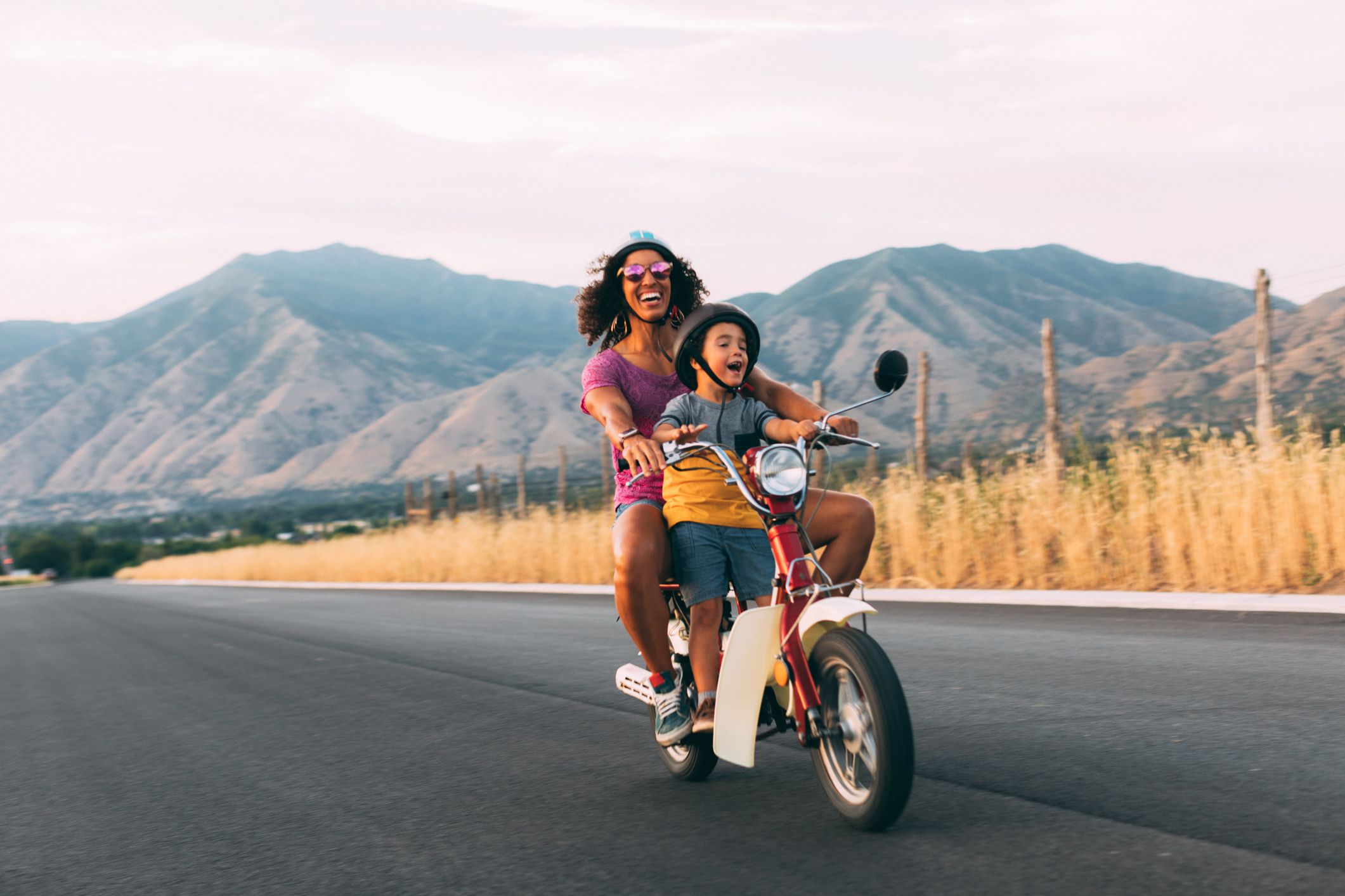 A mother and son enjoy a summer ride on a rural Utah road. They are loving the carefree, fresh air of the afternoon sun. Road trip.