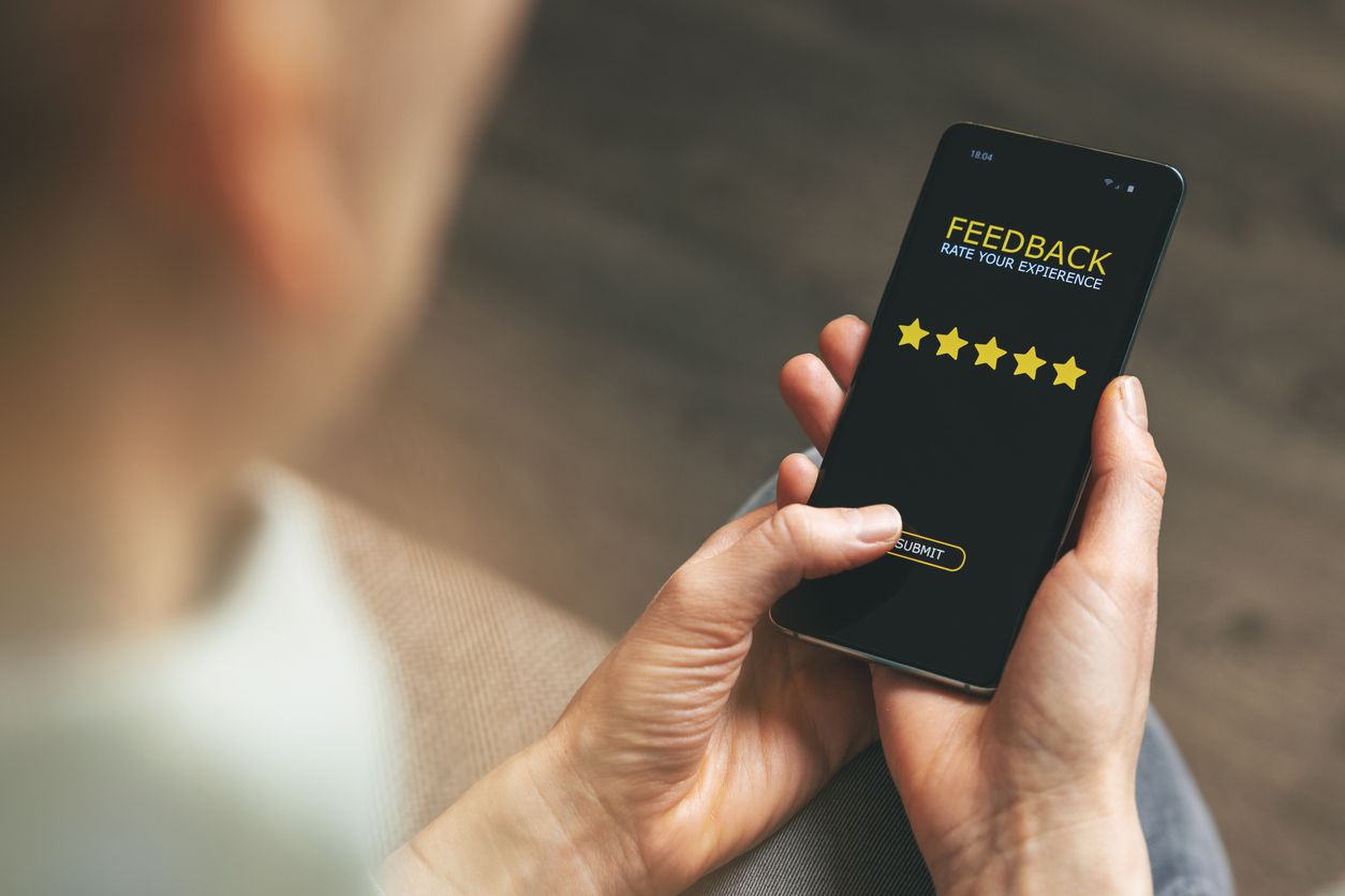 Woman using phone to give 5 star rating for good service feedback