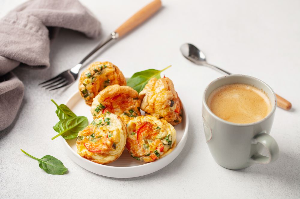 Egg muffins ( bites) and spinach leaves in a plate on a gray background