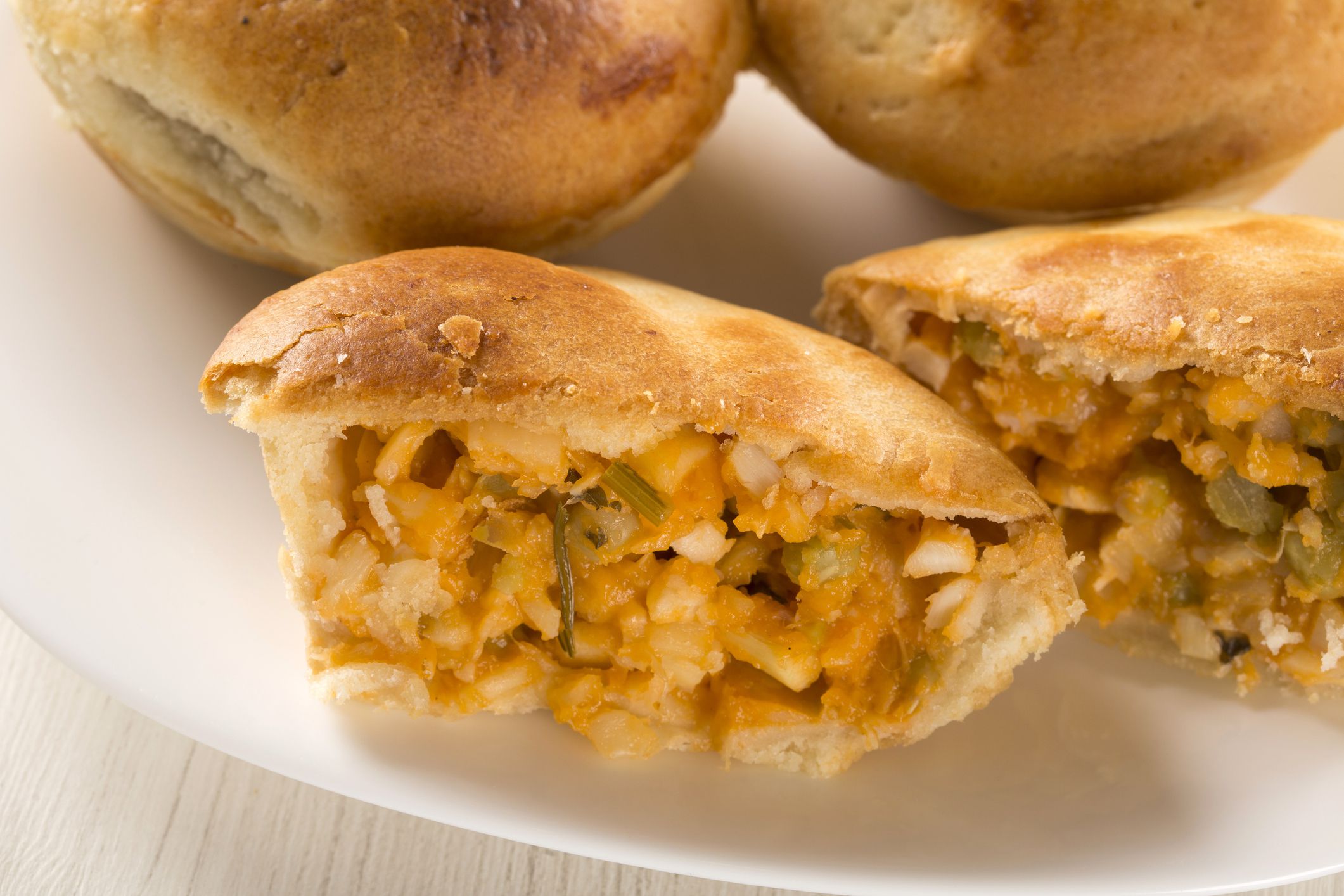 Empada Brazilian snack. pie with palm on white plate on wooden background.