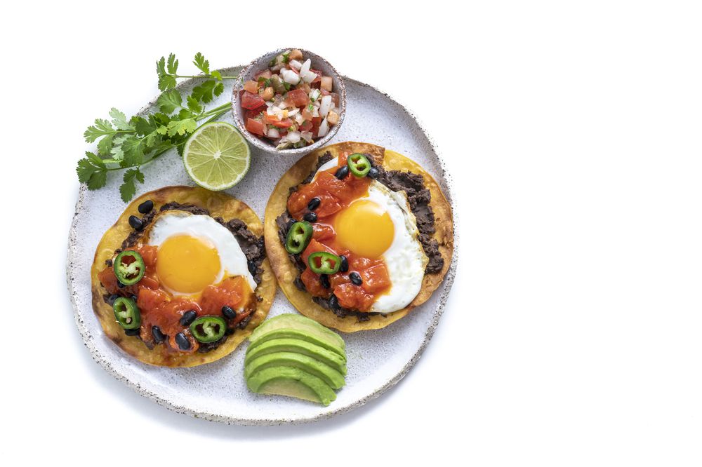 Huevos Rancheros are Mexican Eggs breakfast, guacamole and pico de gallo isolated on white