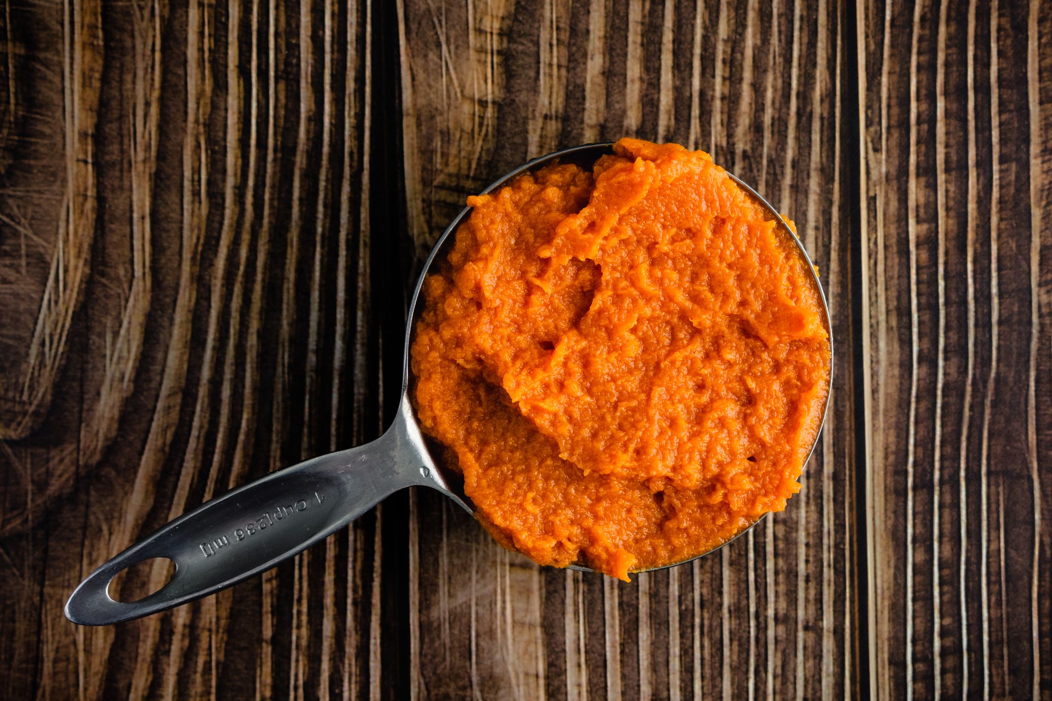 Metal measuring cup filled with pureed pumpkin