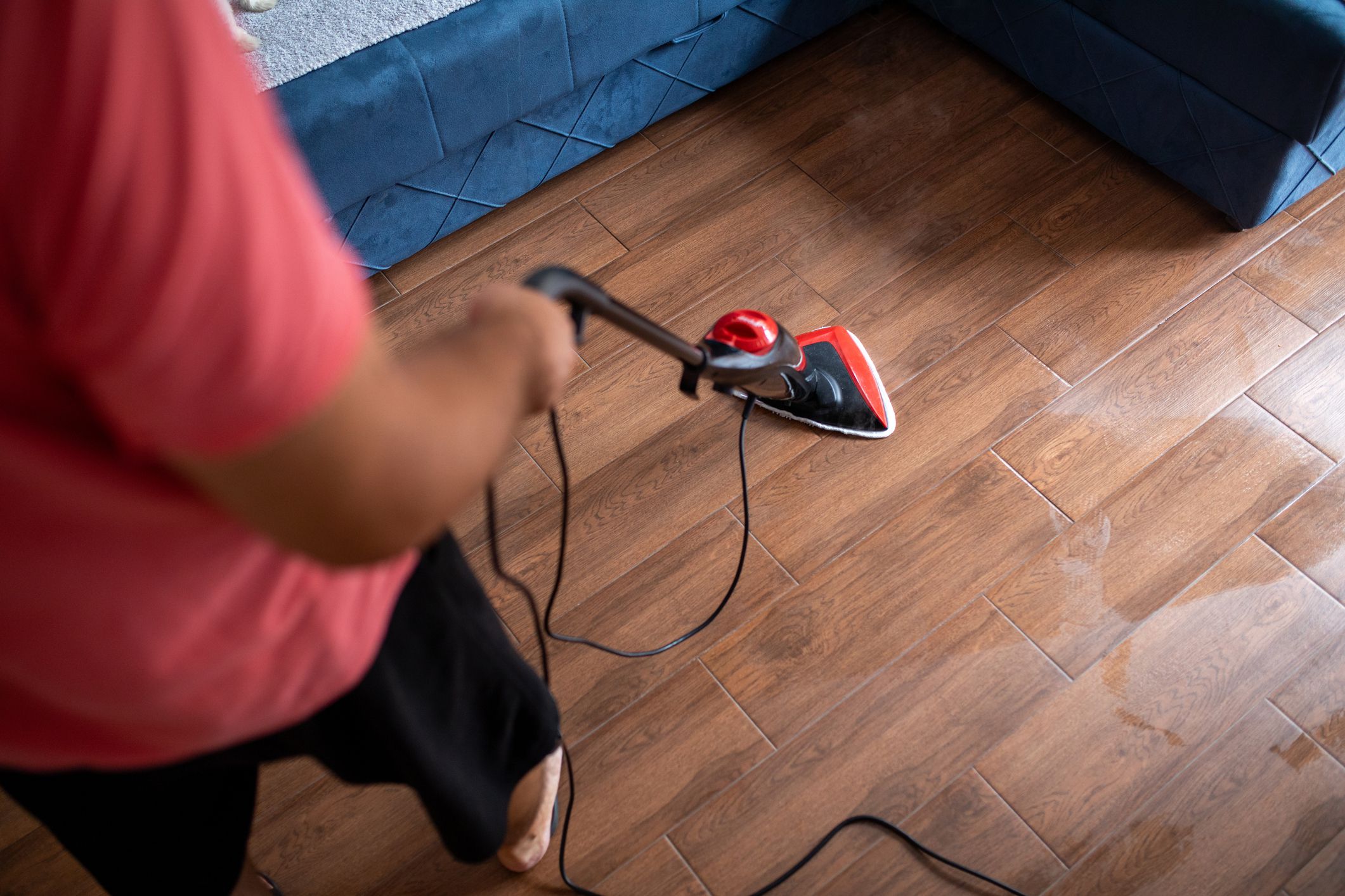 Man cleaning floor with a steam cleaner at home